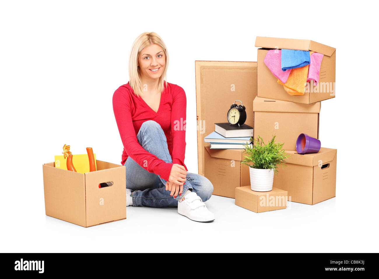 Donna sorridente appoggiato da traslocare in una nuova casa con molte scatole Foto Stock