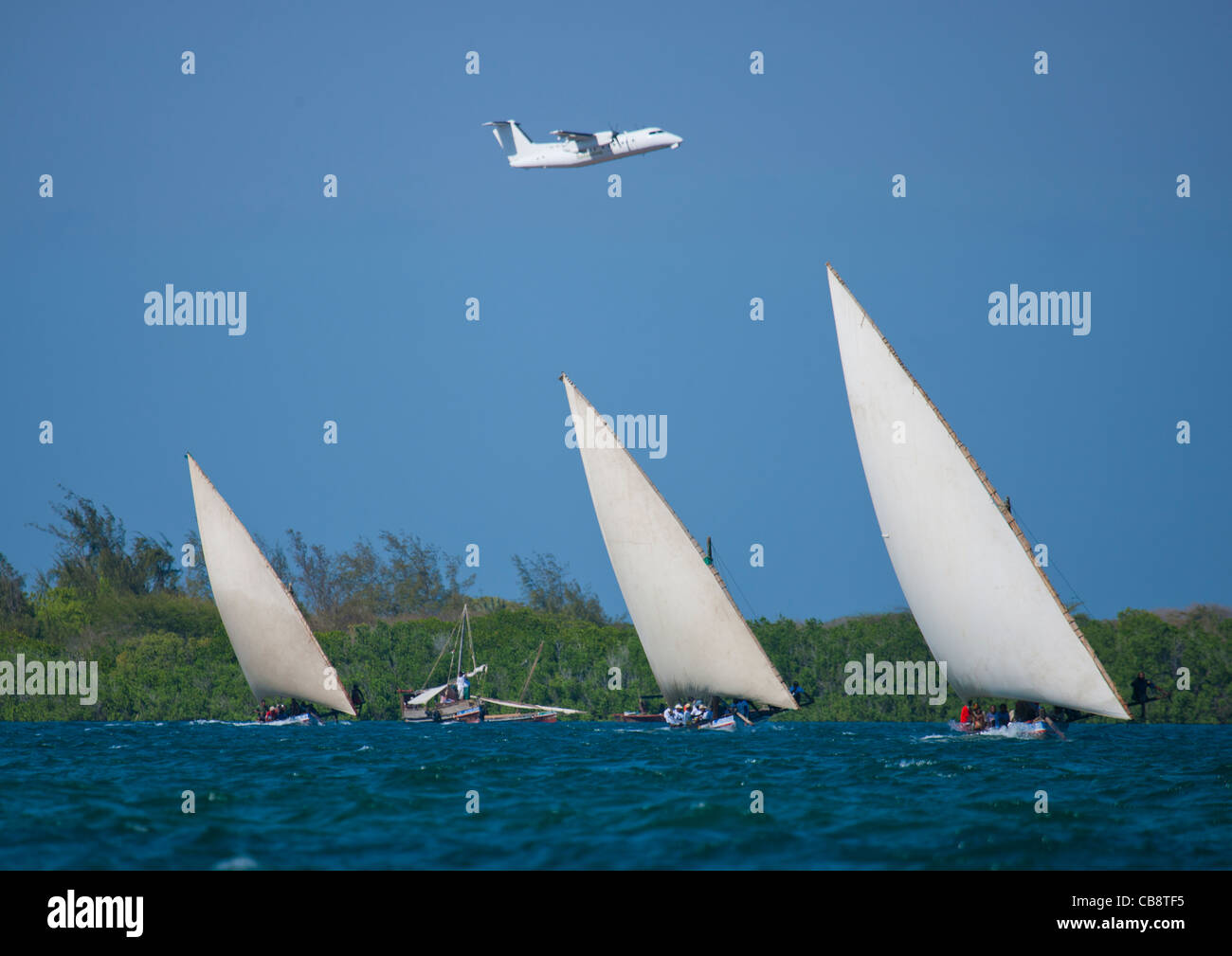 Un piano che passa sopra mentre Dhows Racing nel canale, Lamu, Kenya Foto Stock