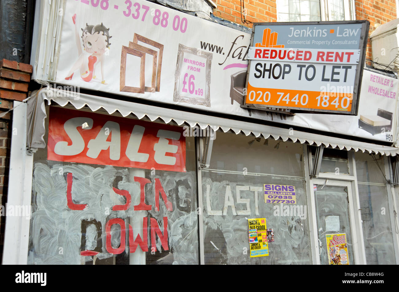 Un negozio di vuoto in un suburbano di Londra high street con 'chiusura di vendita " sulla sua finestra e una scheda Agenti offrendo canone ridotto. Foto Stock