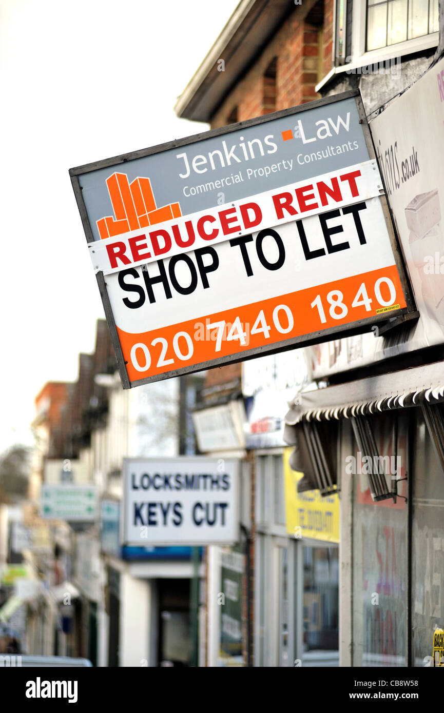 Un negozio di vuoto in un suburbano di Londra high street con 'chiusura di vendita " sulla sua finestra e una scheda Agenti offrendo canone ridotto. Foto Stock