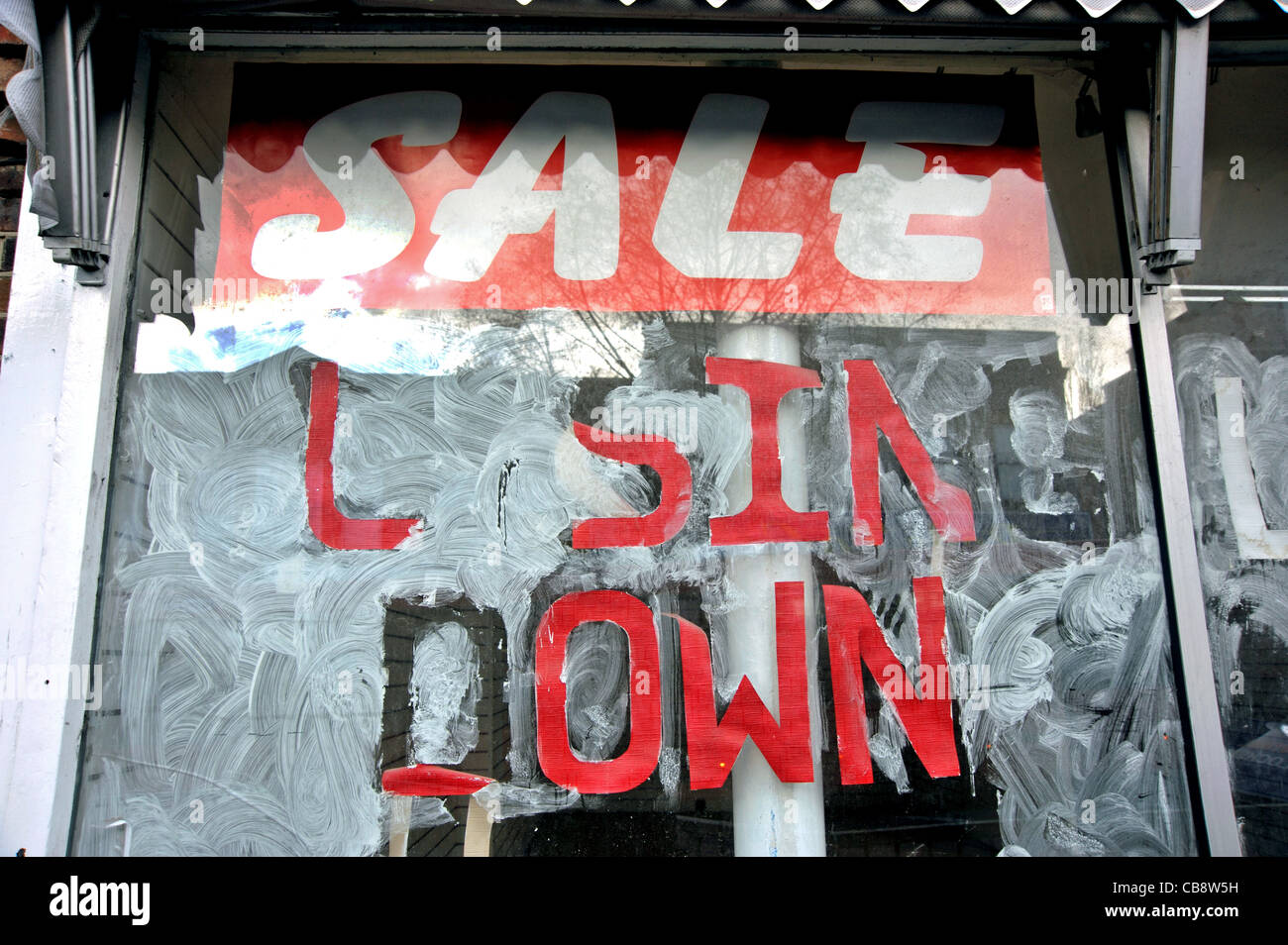 Un vuoto che la finestra del negozio in un suburbano di Londra high street con un 'sale chiusura' segno sulle sue bianche lavate finestra. Foto Stock