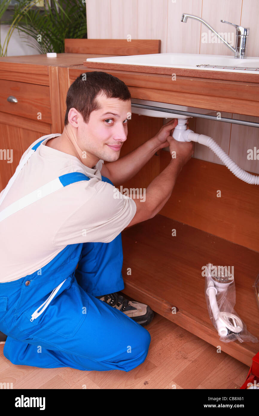 Un idraulico l'impostazione di una tubazione flessibile al di sotto di un rubinetto Foto Stock