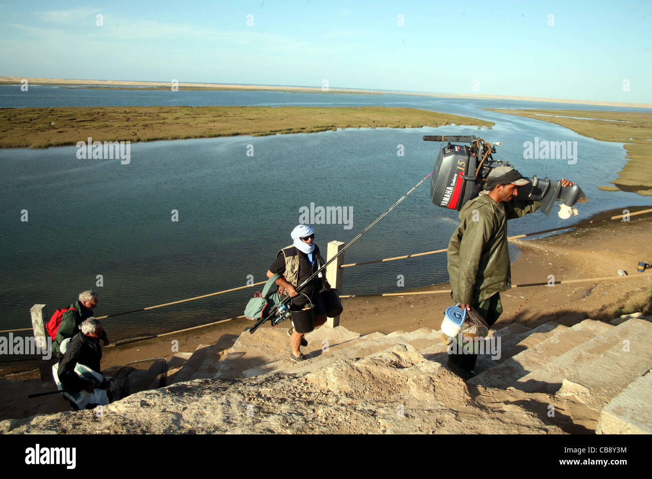 Tre uomini di ritorno dalla pesca su La Naila SW in Marocco Foto Stock