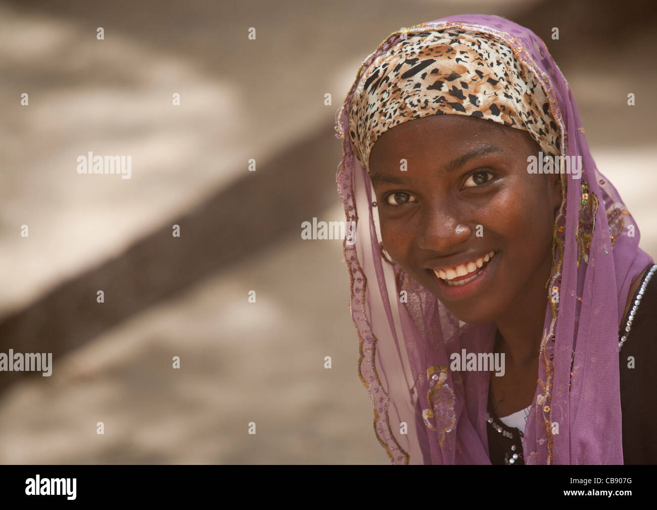 Teenage ragazza carina a Nizza la postura con velo sorridente alla fotocamera, Lamu, Kenya Foto Stock