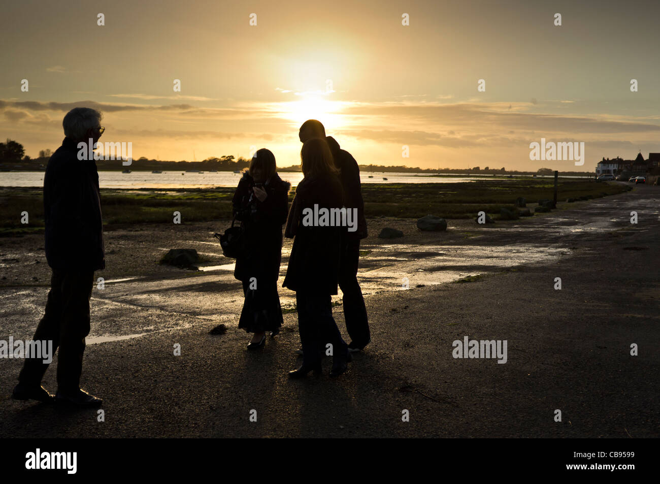 Un gruppo a passeggiare nei pressi di Bosham conla tramonto dietro Foto Stock