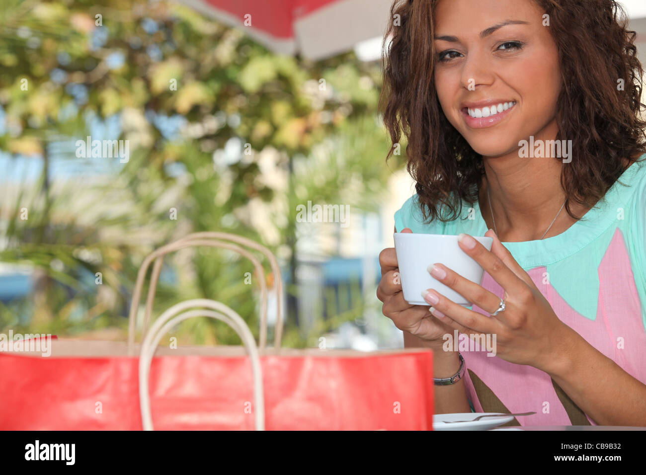 Donna con una borsa da shopping bere il tè al di fuori Foto Stock