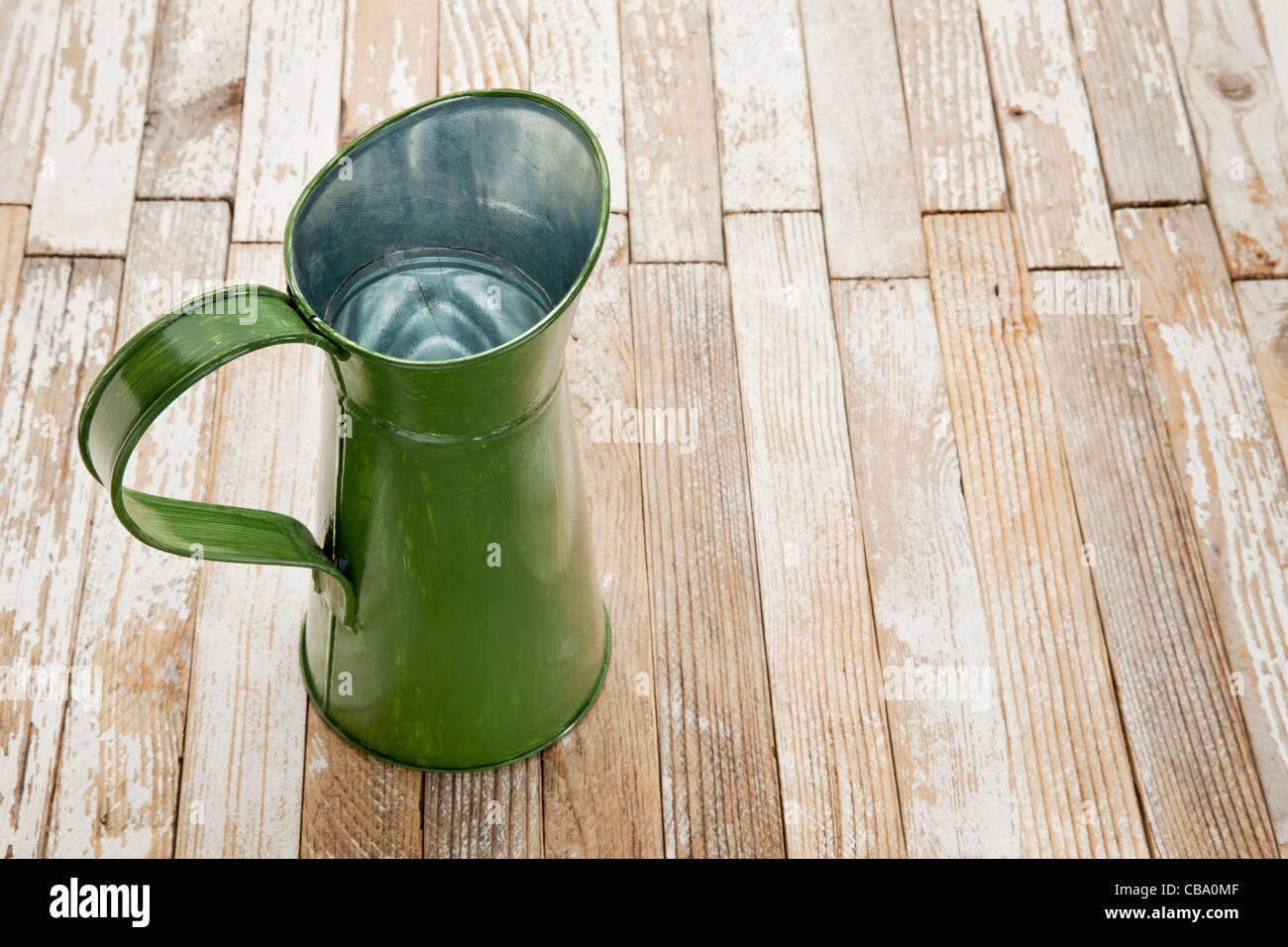 Metallo vintage brocca contro grunge verniciato bianco tavola di legno Foto Stock