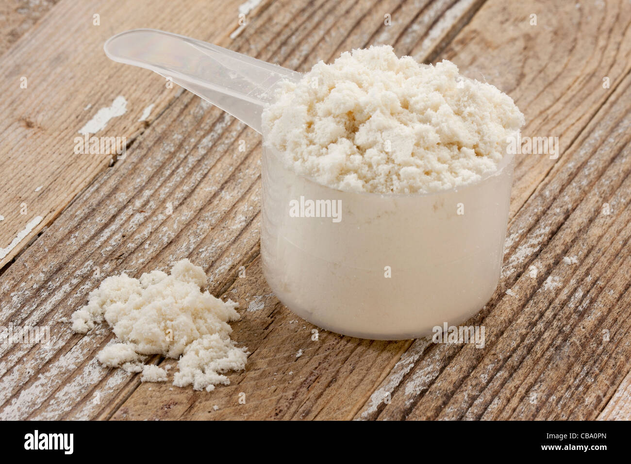 Scoop di isolato di proteina del siero di latte in polvere in un legno di grunge sfondo tabella Foto Stock