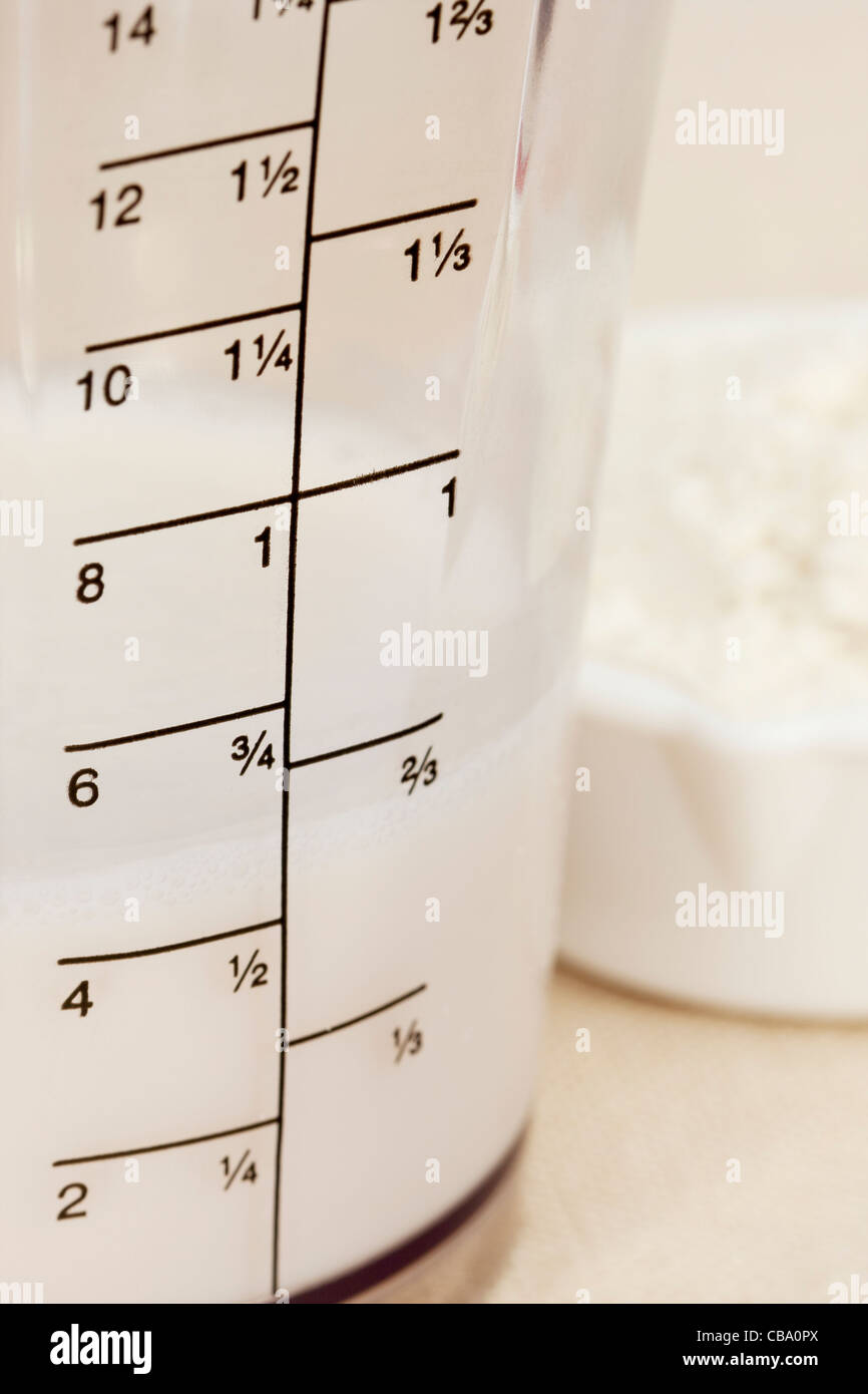 Latte di Mandorla nel bicchiere del frullatore con once e scala di coppa e un cucchiaio di polvere bianca Foto Stock