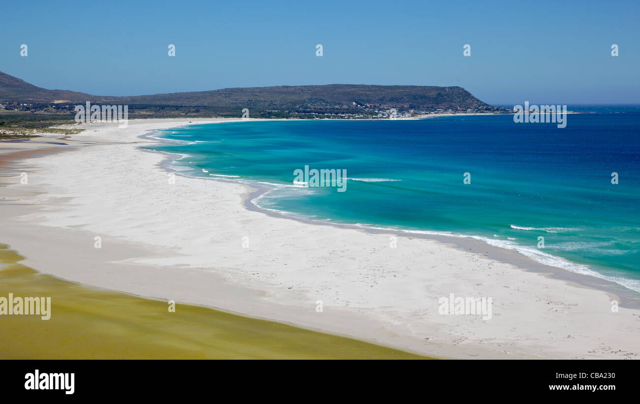 La distesa di spiaggia lunga, con Kommetjie in background, Penisola del Capo, in Sud Africa. Foto Stock