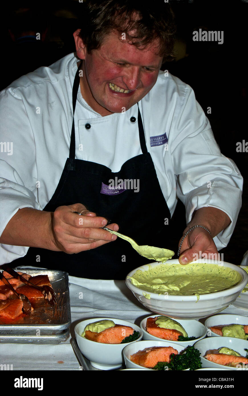 Ristorazione Lo chef spooning crème fraiche salsa verde salsa ciotola il salmone cotto broccoli orzo Foto Stock