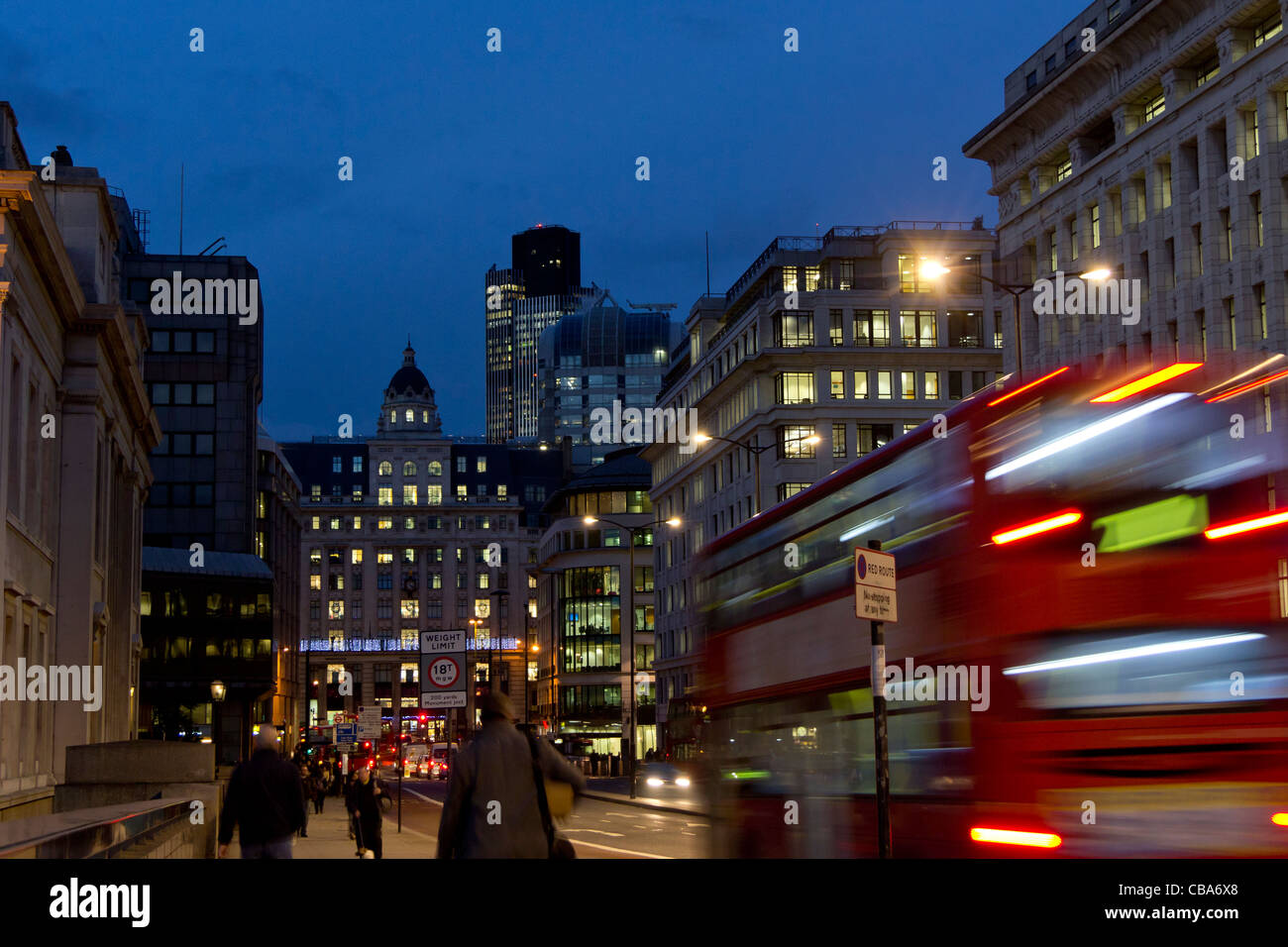 Vista lungo la King William Street da London Bridge dei lavoratori a piedi home al calar della sera e sfocata motion London bus. Foto Stock