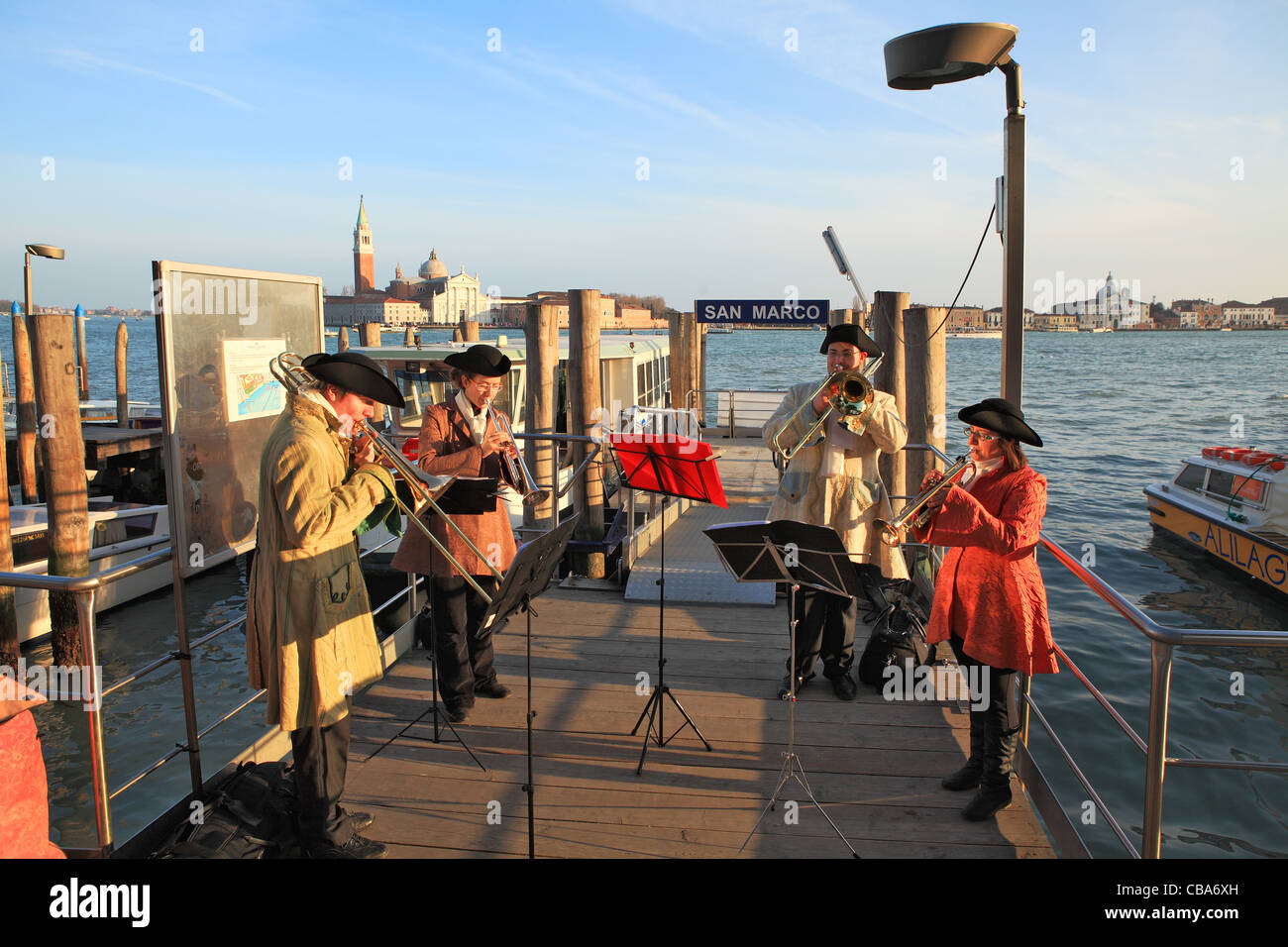 Banda musicale nei tradizionali costumi di carnevale riproduzione di musica classica presso il molo sul Canal Grande durante il carnevale veneziano. Foto Stock