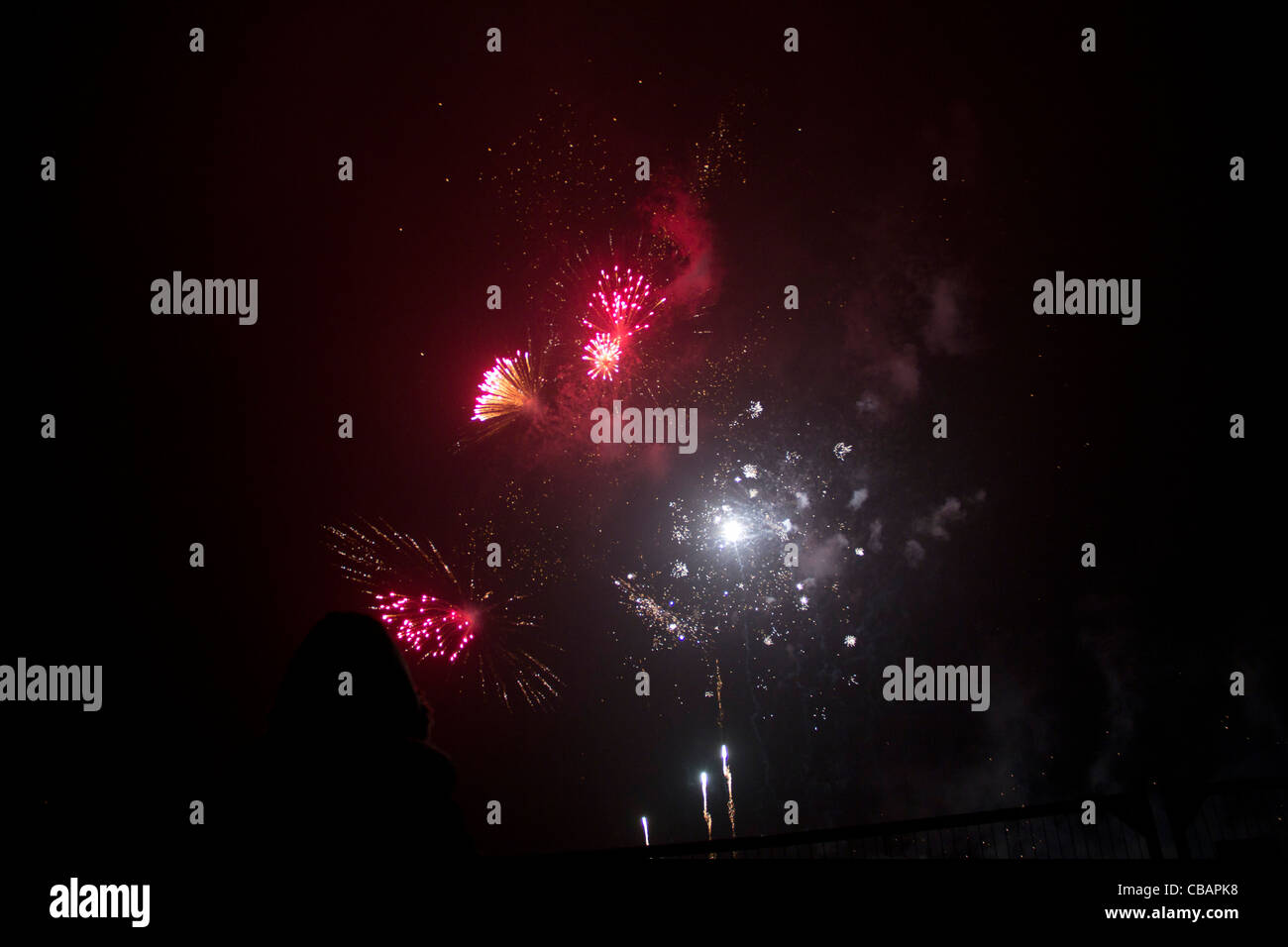 I fuochi d'artificio in Londra. Piccolo rosso brillante, rosa e bianco esplosioni illuminano il cielo di notte creando un bello spettacolo. Foto Stock