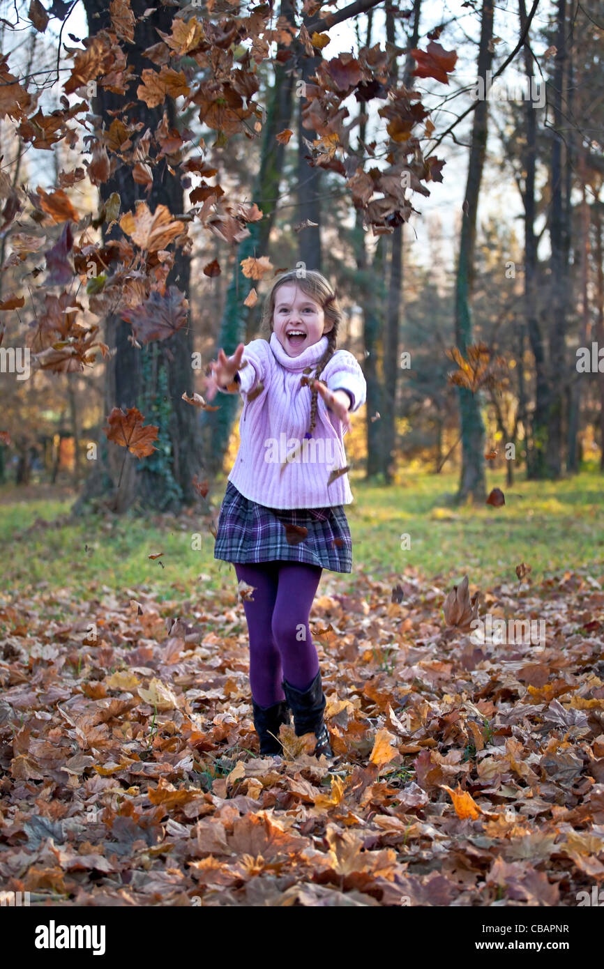 La ragazza sta giocando nei boschi con fogliame di autunno Foto Stock