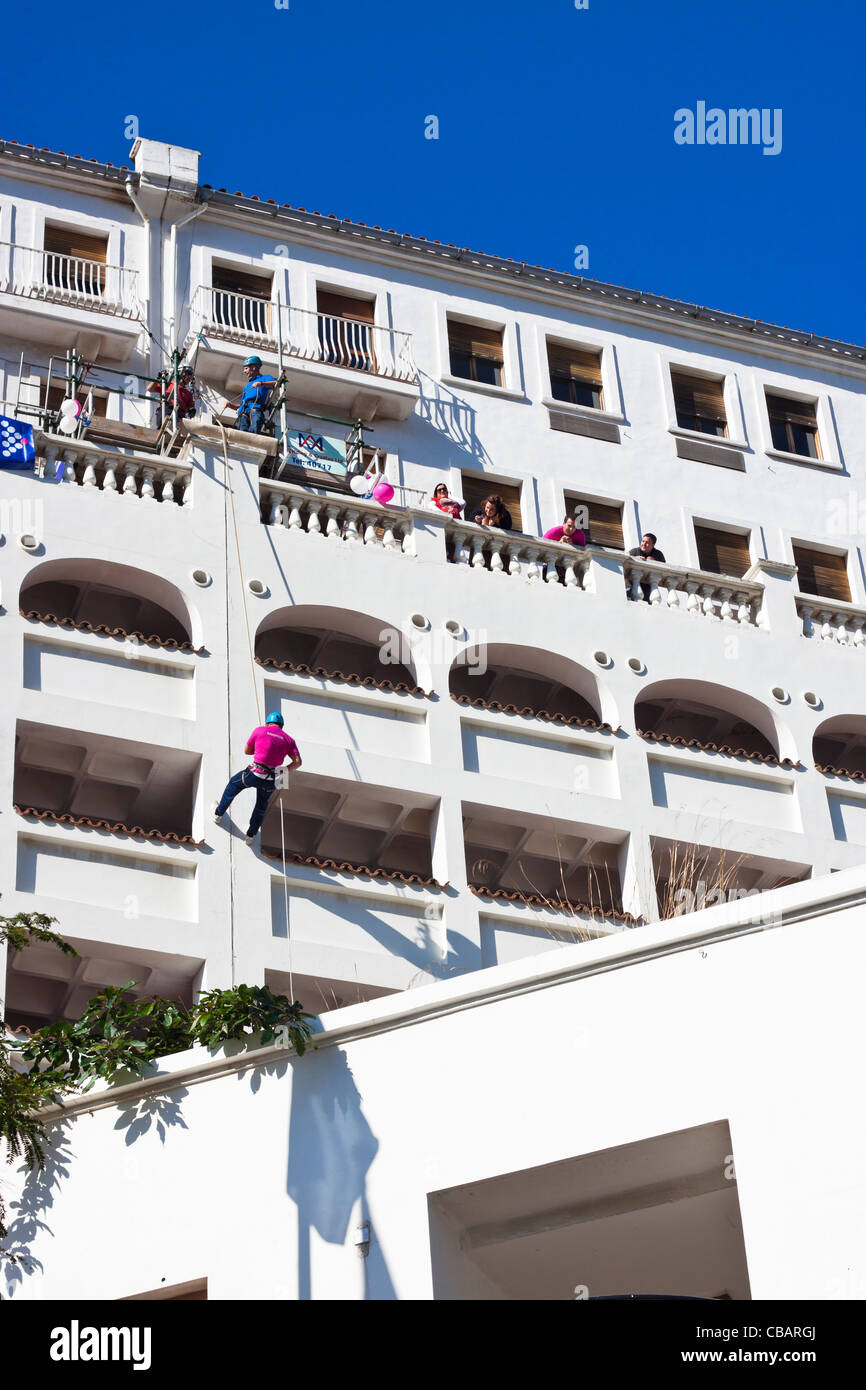 Un uomo rappels un edificio per carità, Main Street, Gibilterra. Foto Stock
