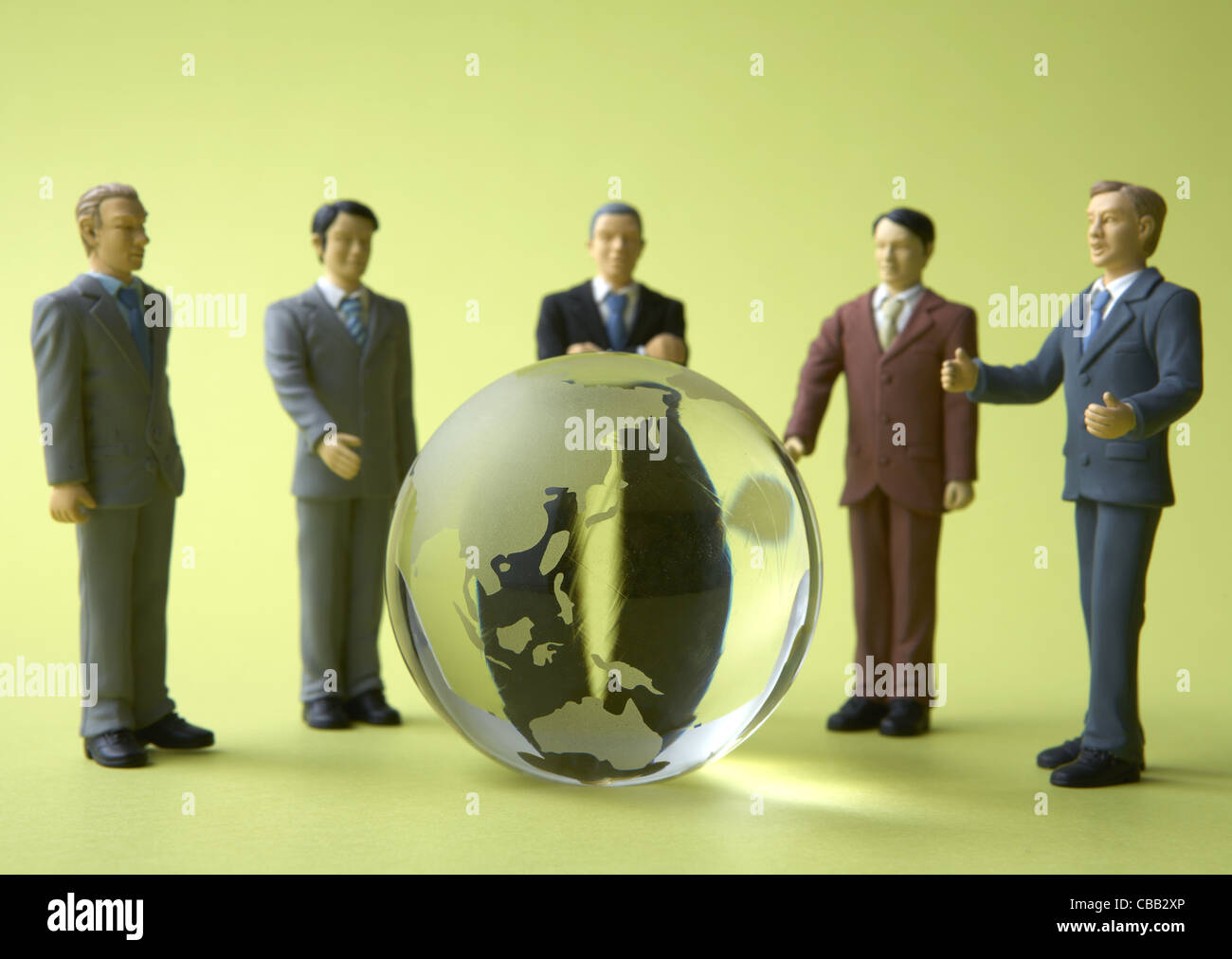 Gli imprenditori in miniatura che circonda globo di vetro Foto Stock