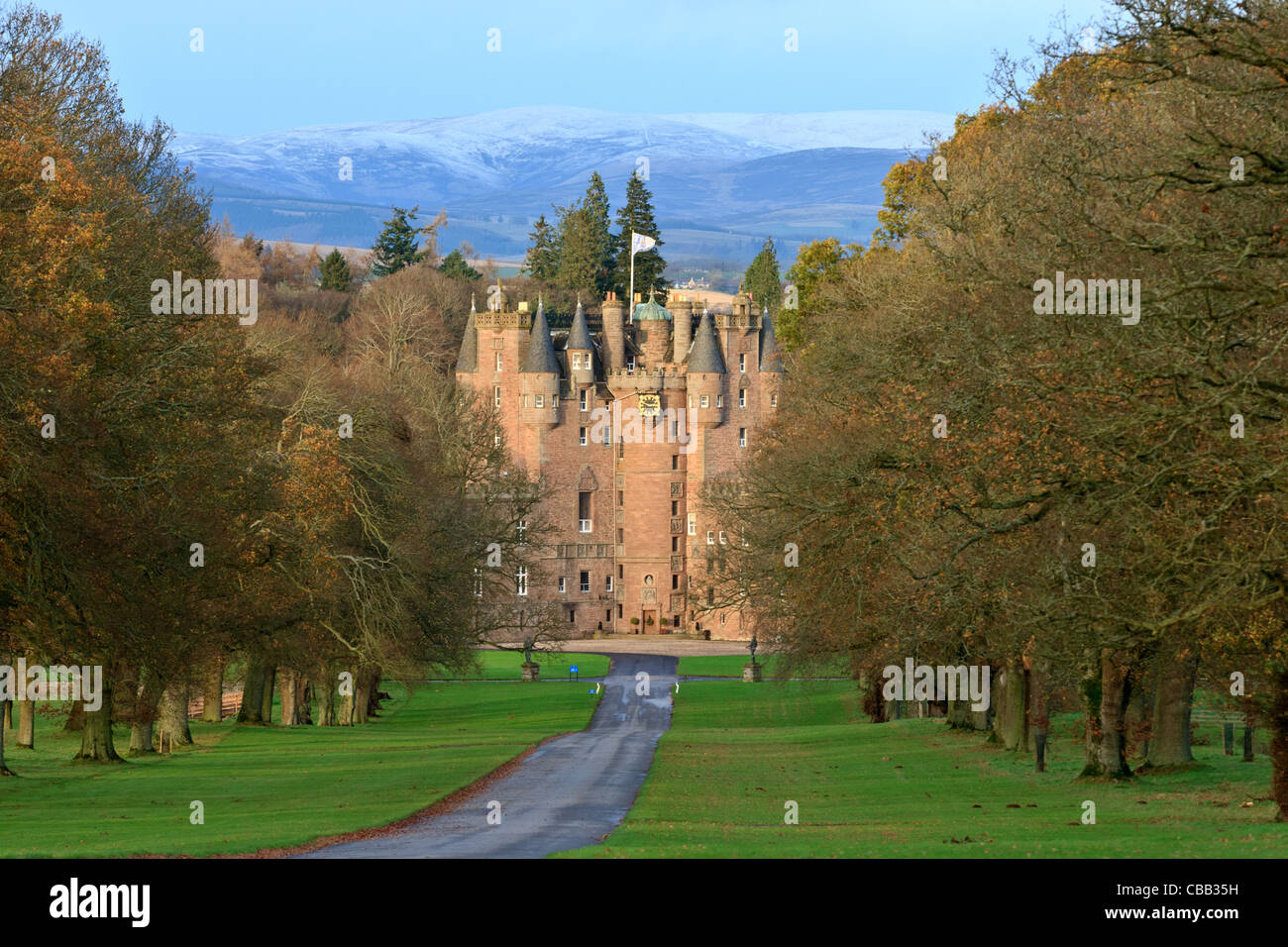 Il vialetto che conduce al e la parte anteriore del Glamis Castle in Scozia in una giornata autunnale con montagne innevate della distanza Foto Stock