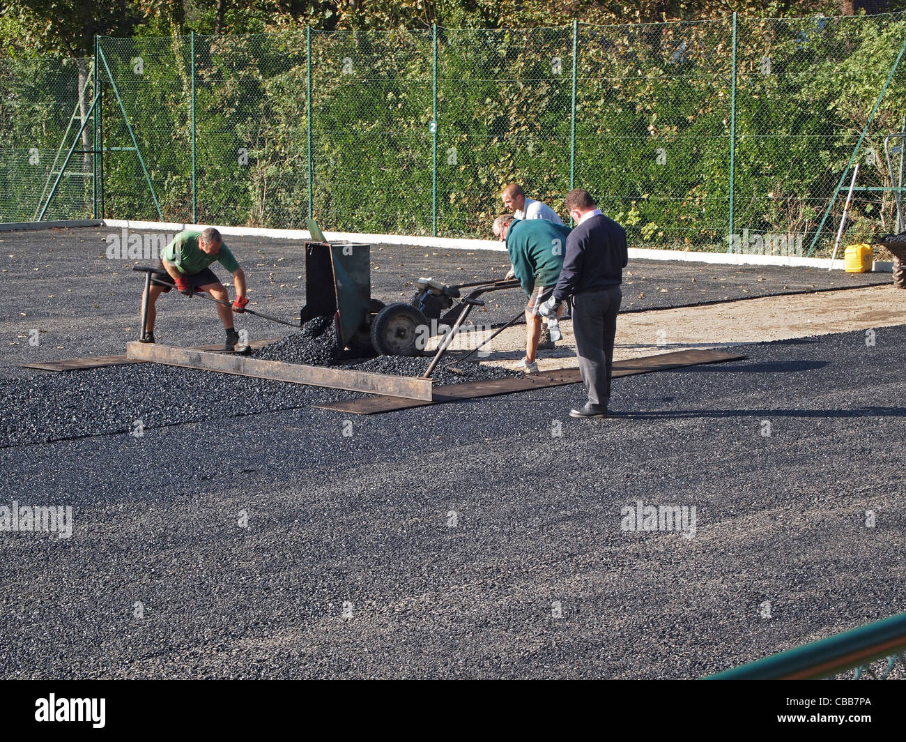 Costruzione di argilla sintetico campi da tennis - la base macadam strato viene livellato e compattato Foto Stock