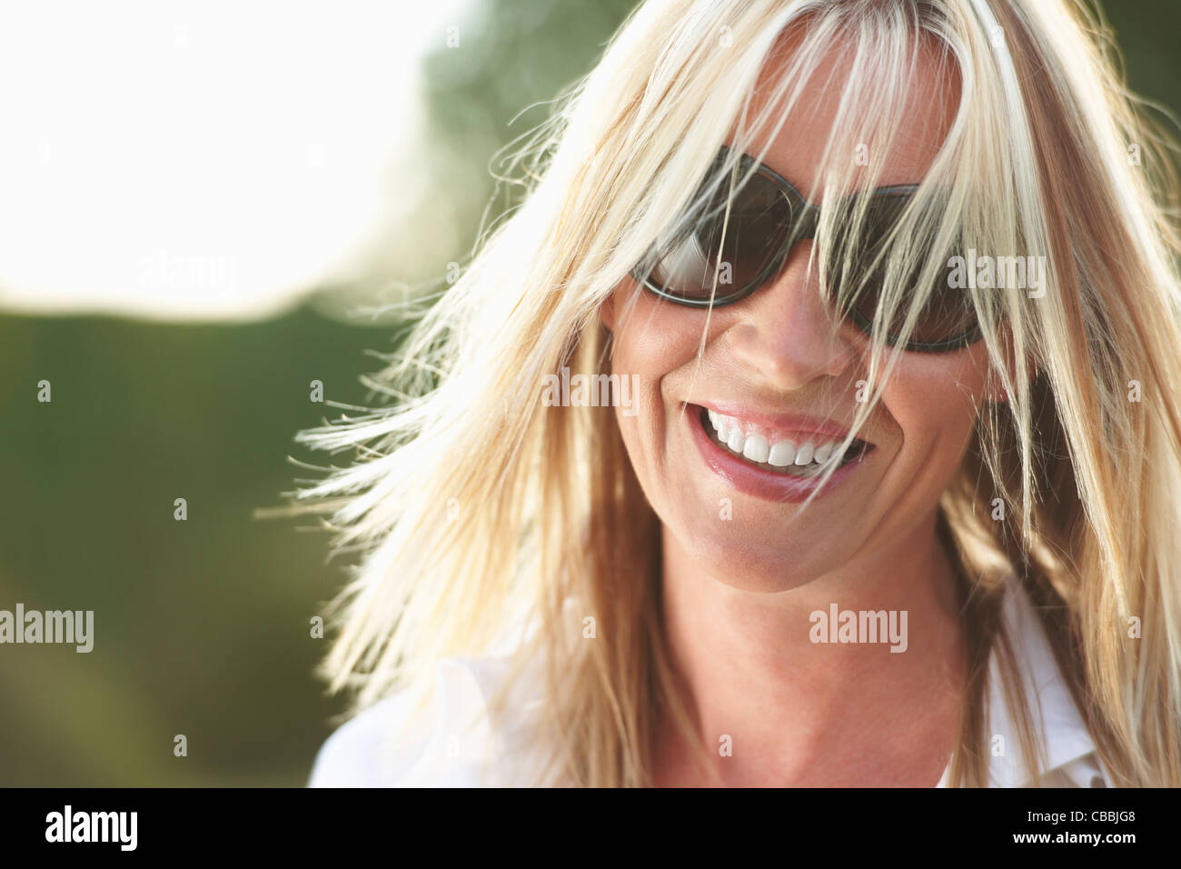 Donna sorridente con occhiali da sole Foto Stock