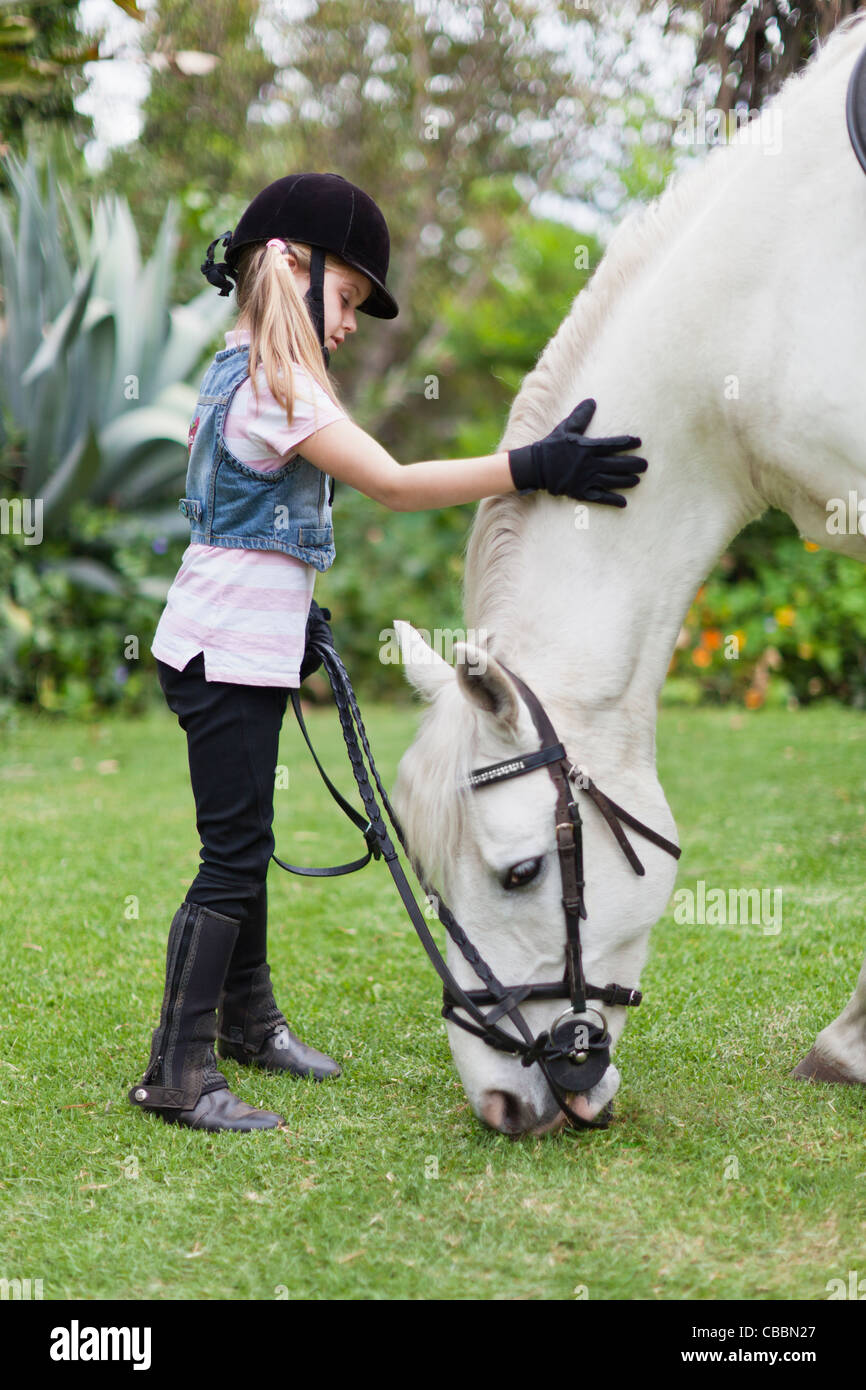 Ragazza petting cavallo al pascolo in posizione di parcheggio Foto Stock