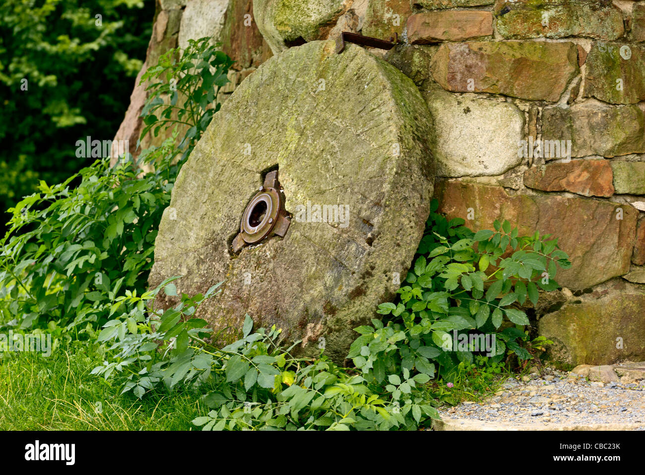 Pietra di mulino a lato dell'edificio Foto Stock