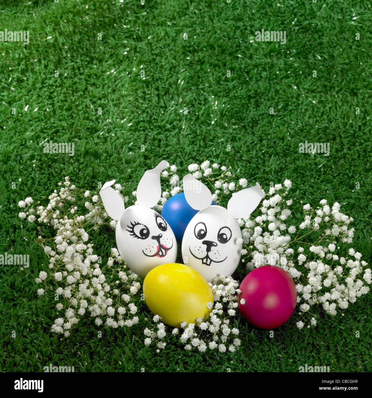 "Bunny" con stile le uova di pasqua in decorazioni floreali e artificiali erba verde sullo sfondo Foto Stock