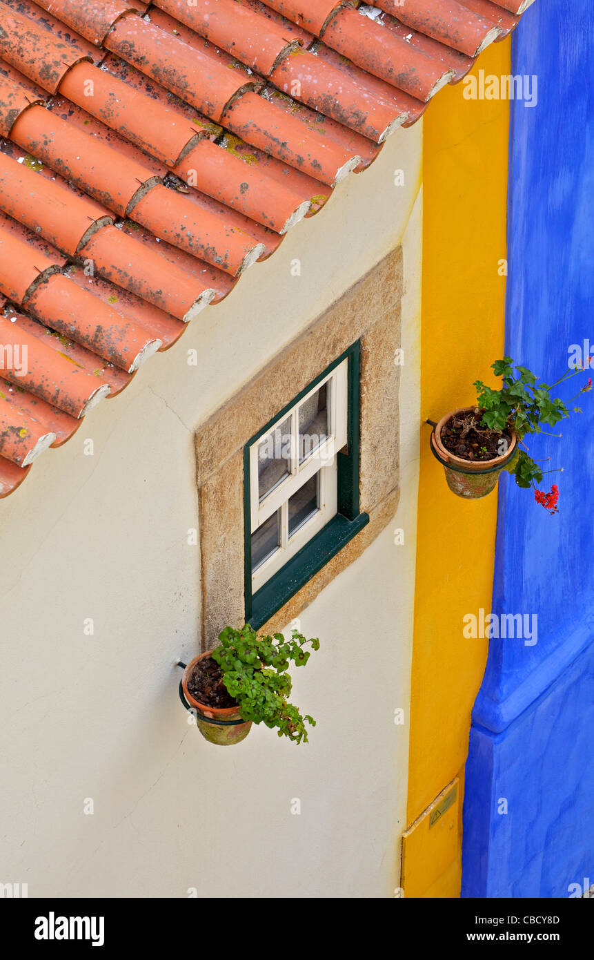 Finestra di argilla e tetto in tegole con un pastello colorato parete nel borgo medievale di Obidos Foto Stock