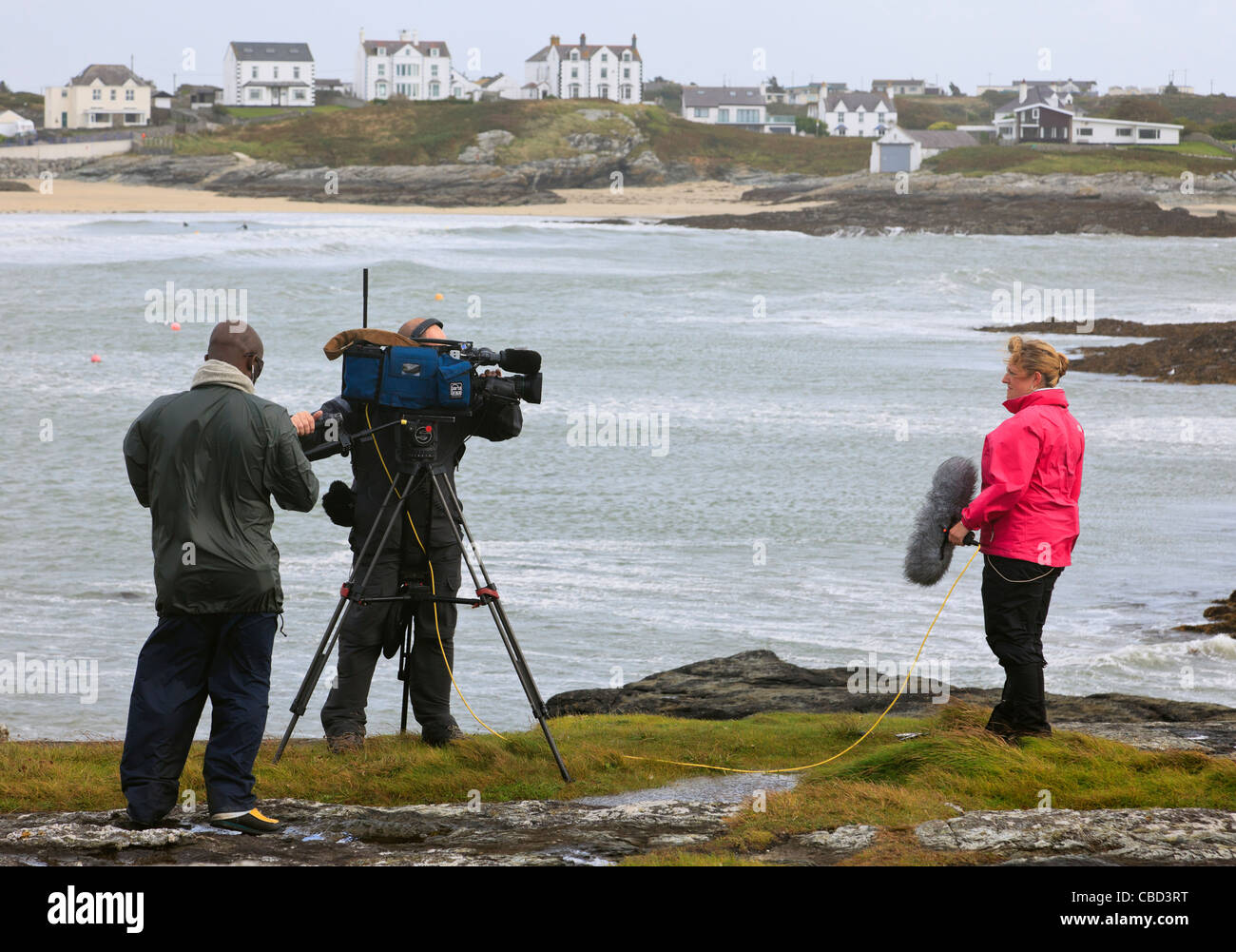 Regno Unito live BBC news reporter e troupe reporting gravi ventoso con gales in Welsh west coast. Foto Stock