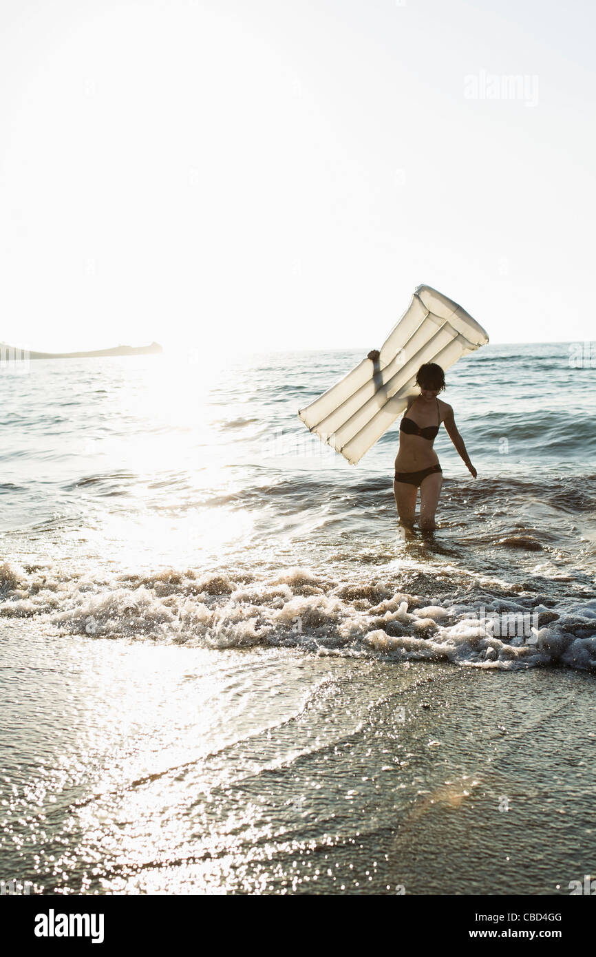 Donna con materasso gonfiabile sulla spiaggia Foto Stock