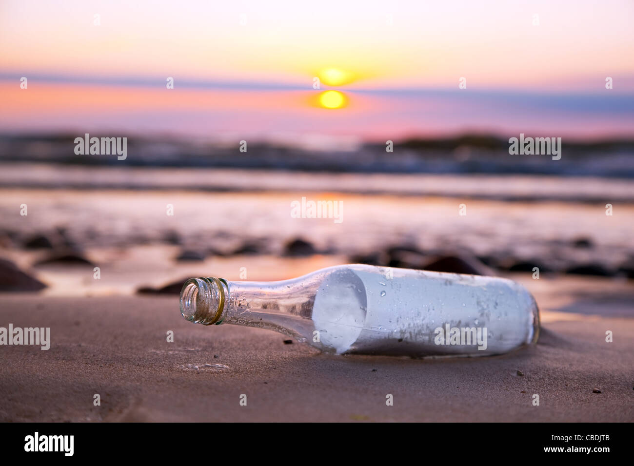 Un messaggio in bottiglia dal mare sulla spiaggia al tramonto Foto Stock