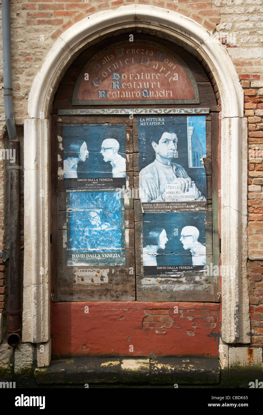 Poster d'arte consumati su una vecchia porta di mattoni a Venezia, Italia Foto Stock