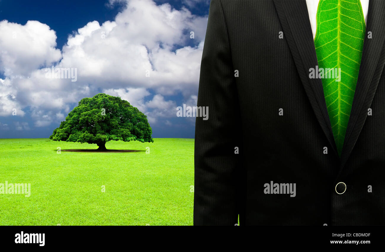 Green Business concetto.imprenditore con cravatta in foglia e il vecchio albero sullo sfondo Foto Stock