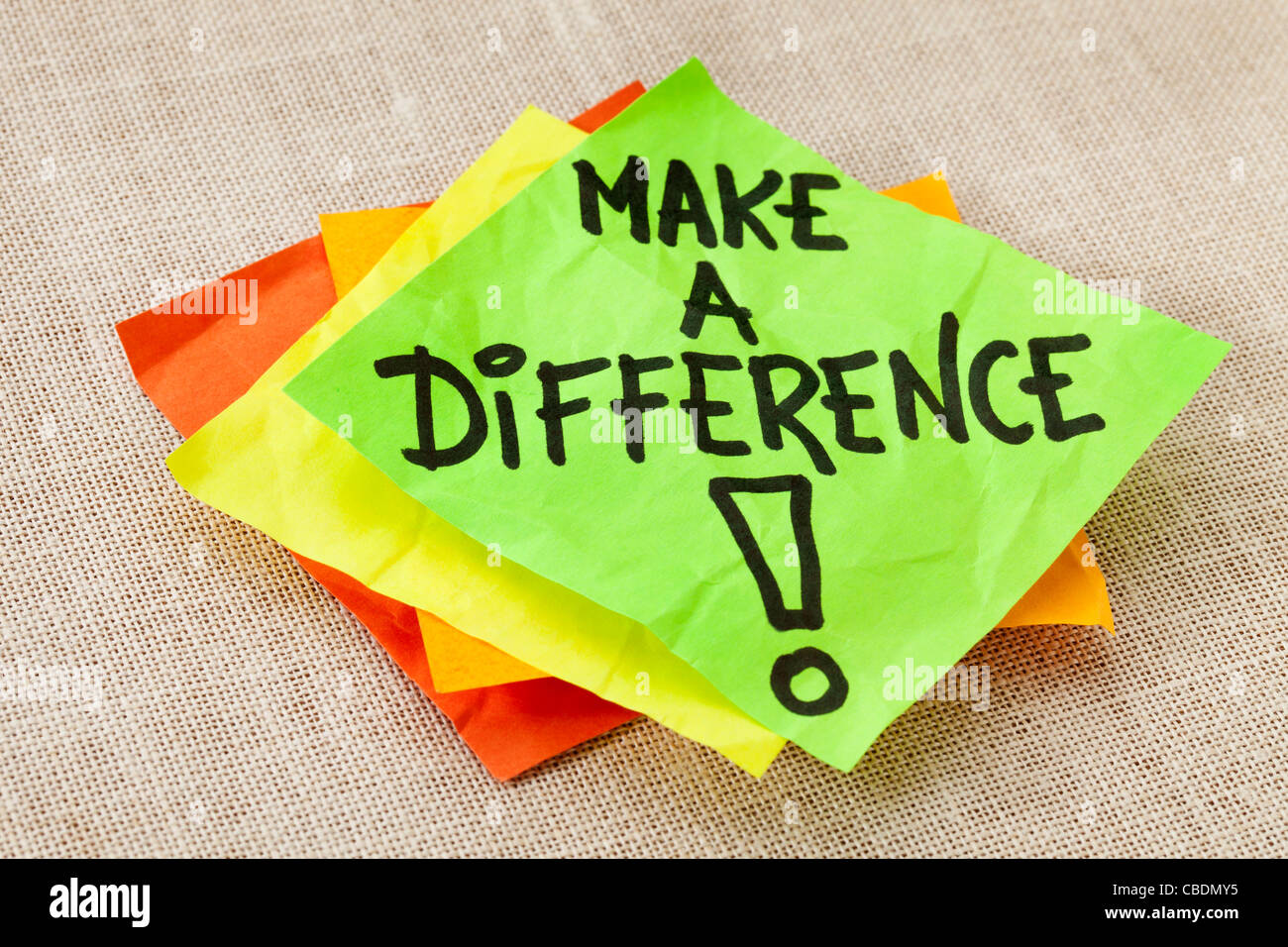 Fare la differenza - Promemoria motivazionale sul verde nota adesiva contro il cartone telato Foto Stock