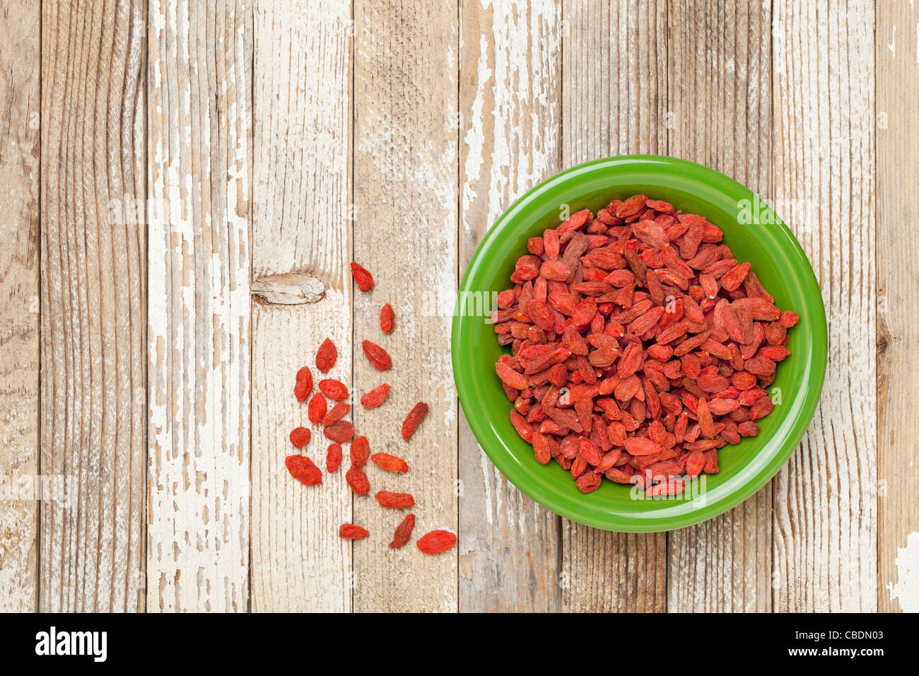 Essiccato Tibetan goji bacche (wolfberries) nel verde di un vaso in ceramica su grunge dipinte di bianco superficie di legno Foto Stock