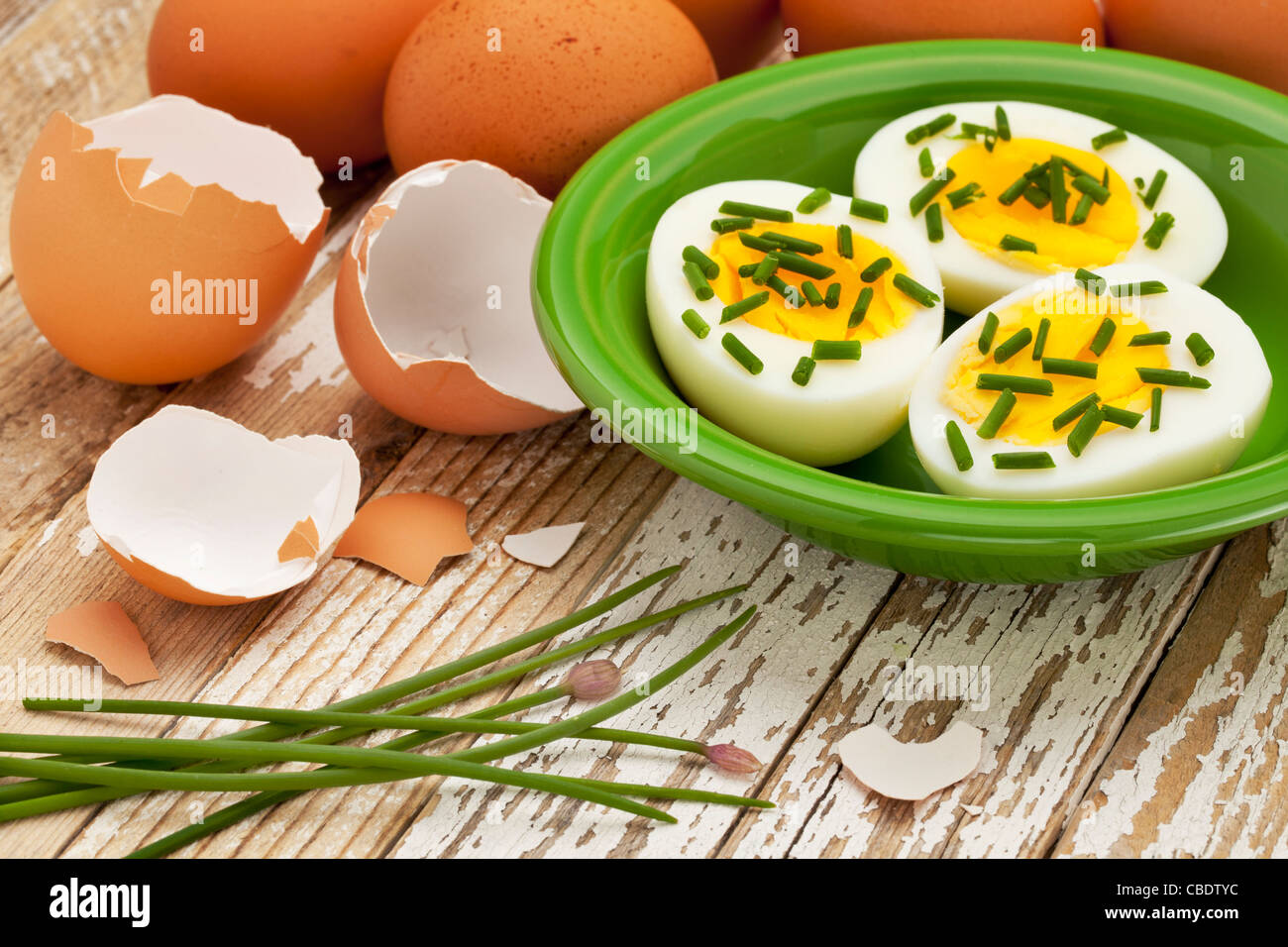 Bollite le uova di pollo con verde erba cipollina contro grunge superficie di legno - Pasqua o concetto della molla Foto Stock