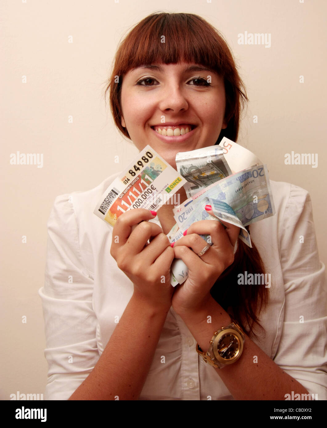 Una giovane donna sorridente con vincente un biglietto della lotteria e denaro nelle sue mani Foto Stock