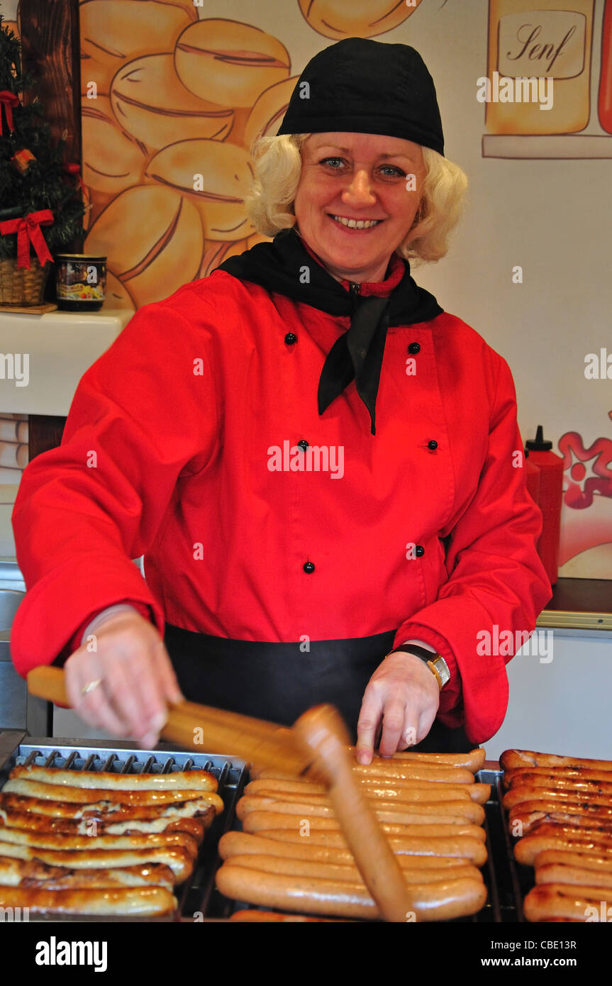 Donna che lavorano presso il bratwurst stallo in mercato di Natale, Rathausplatz, Hamburg, Amburgo Regione Metropolitana, Germania Foto Stock