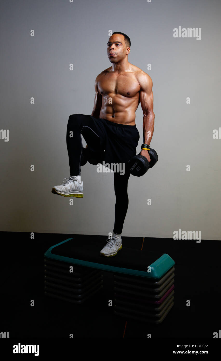 Uomo nero lavorando in palestra con barbells e la fase di scatole. Foto Stock