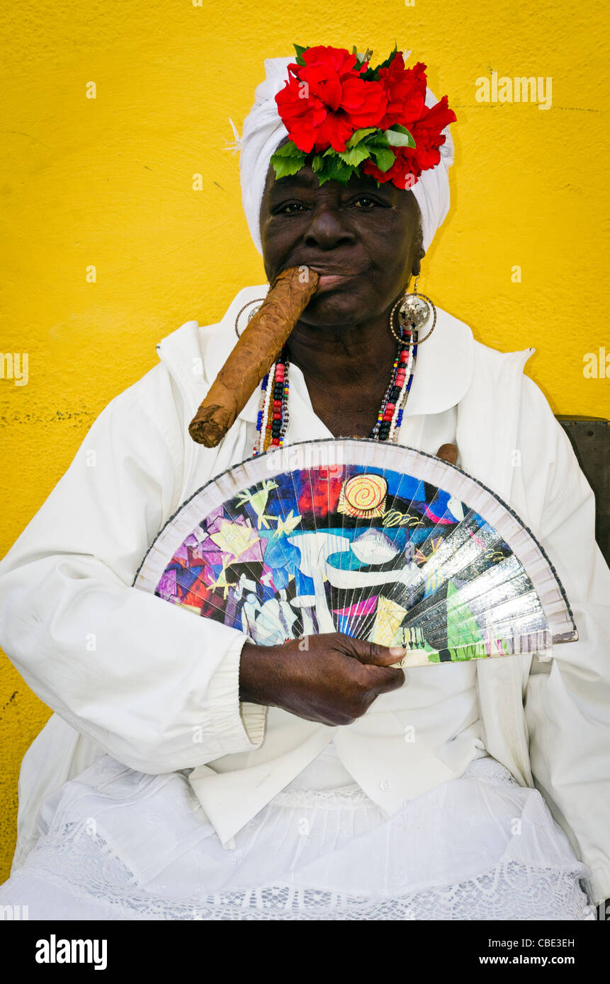 Donna cubana che indossa un Santeria abito bianco di fumare un sigaro di grandi dimensioni La Habana Vieja La Habana Cuba Foto Stock
