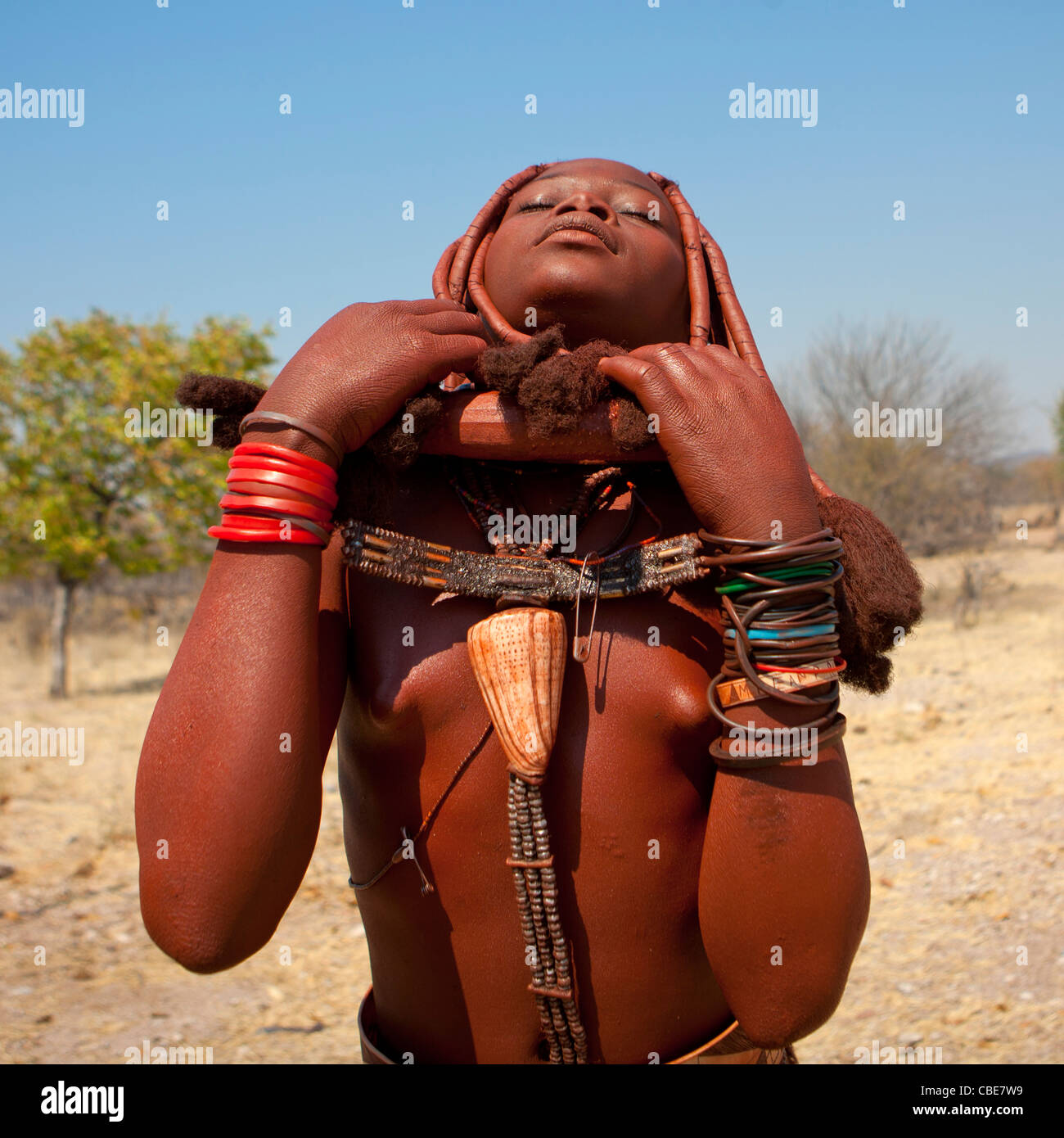Ragazza Himba chiamato Manginete Ajusting la sua collana di rame, villaggio di Hoba Haru, Angola Foto Stock