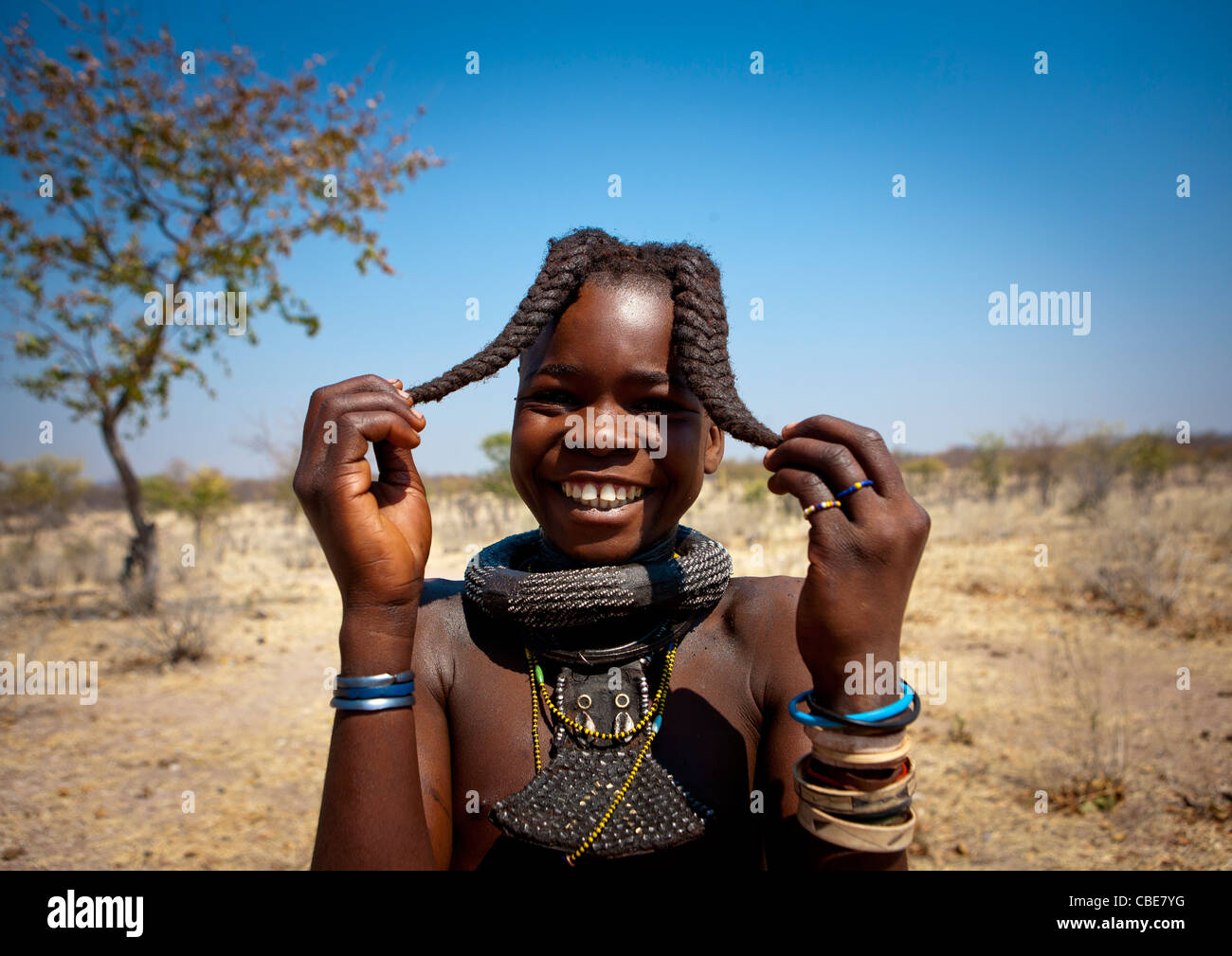 Ragazza Himba chiamato Kamundomba tenendo le sue due trecce, villaggio di Habu Haru, Angola Foto Stock