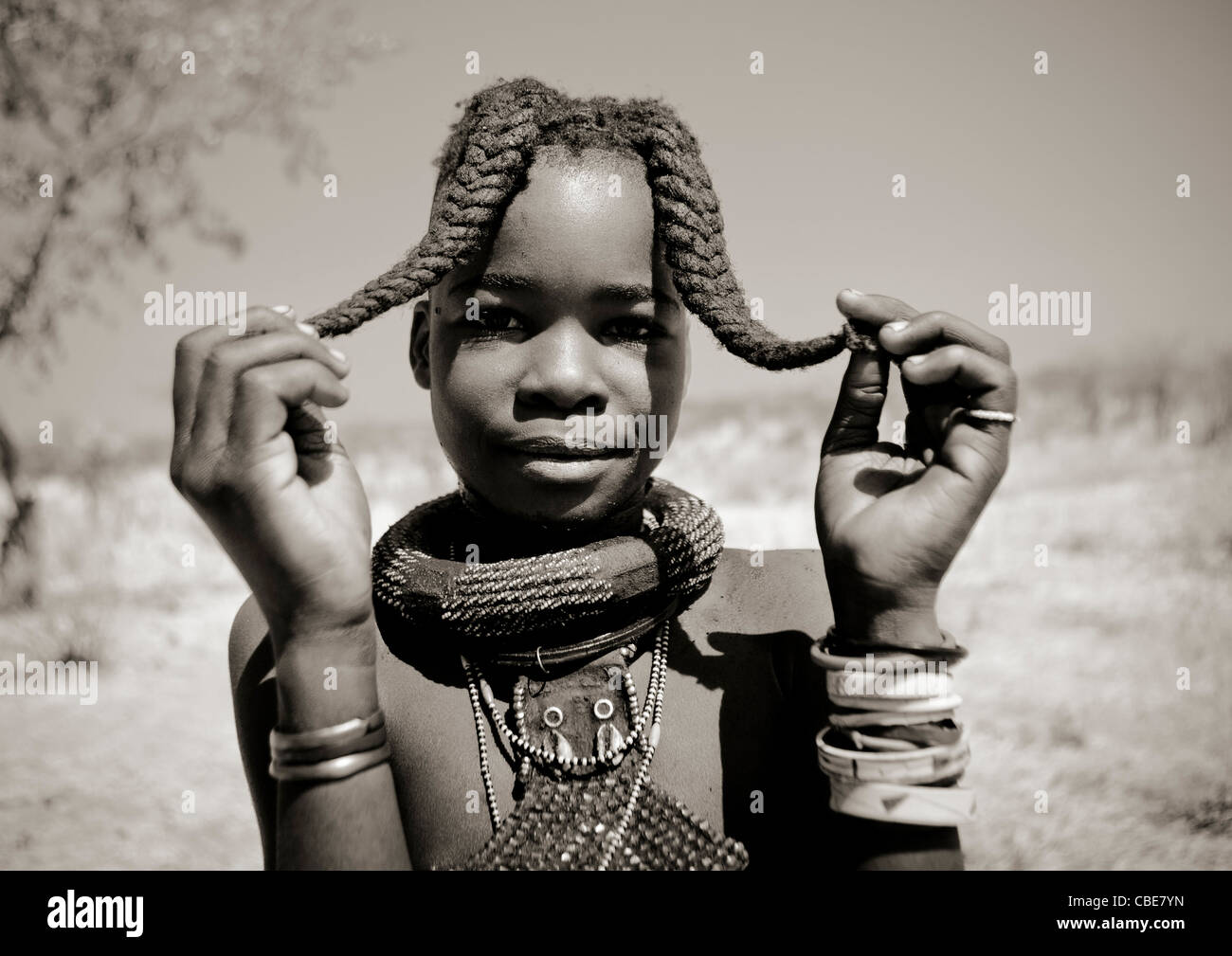 Ragazza Himba chiamato Kamundomba tenendo le sue due trecce, villaggio di Habu Haru, Angola Foto Stock