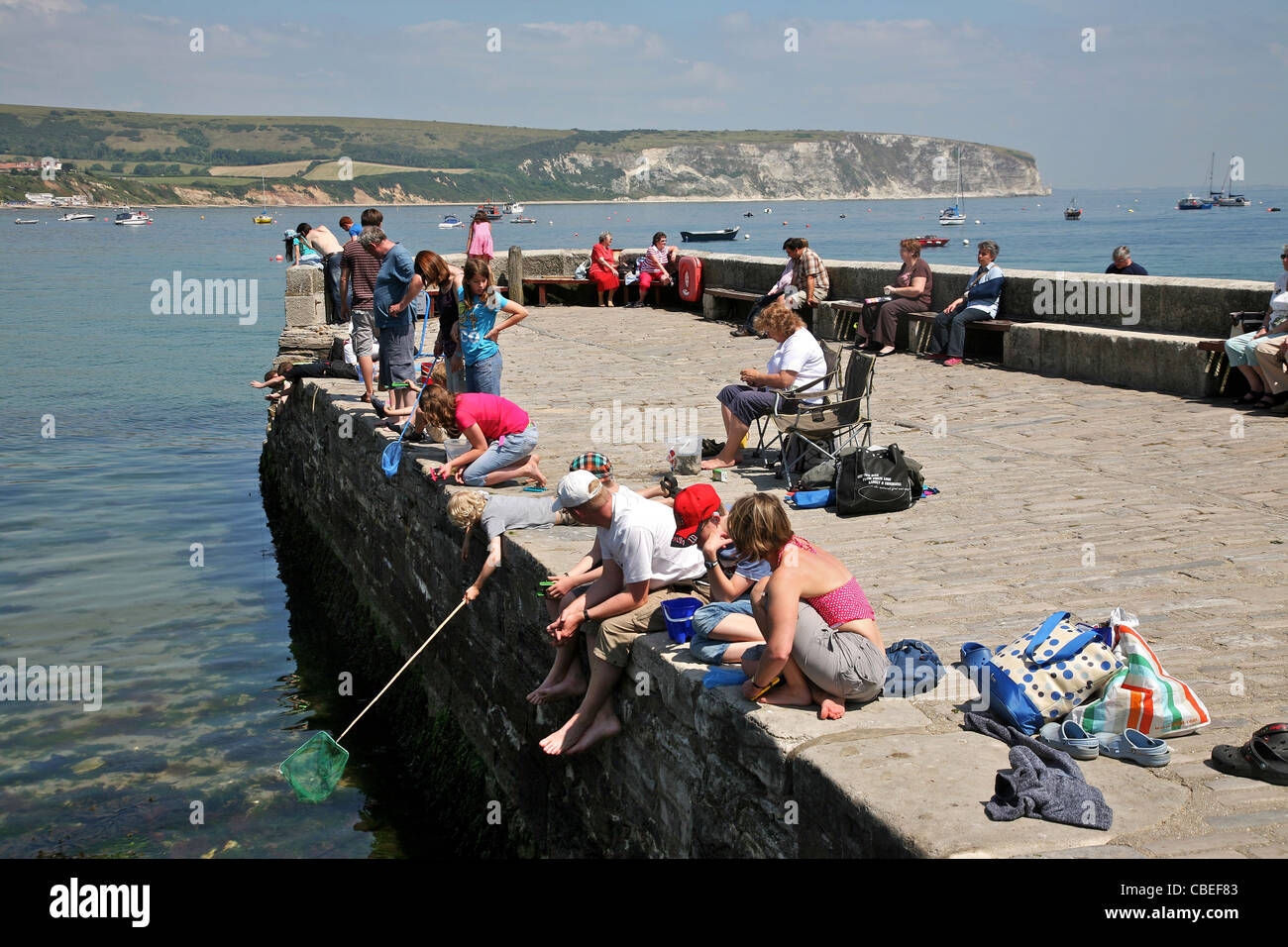 I visitatori la pesca dal molo di pietra nella famosa località balneare di Swanage Foto Stock