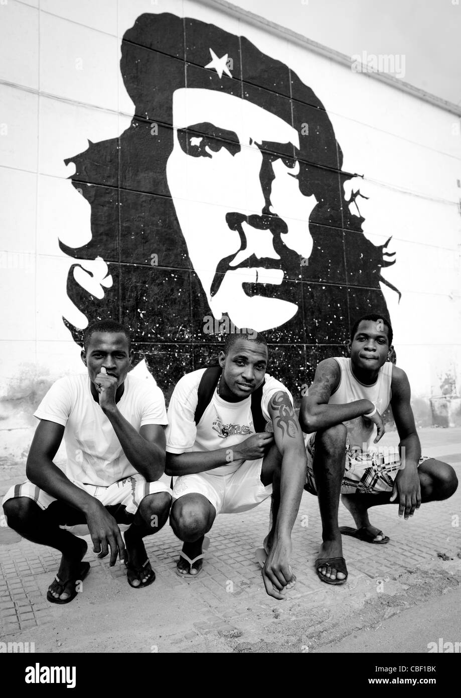Gli uomini rannicchiato nella parte anteriore di un Che Guevara dipinto murale, Sumbe, Angola Foto Stock