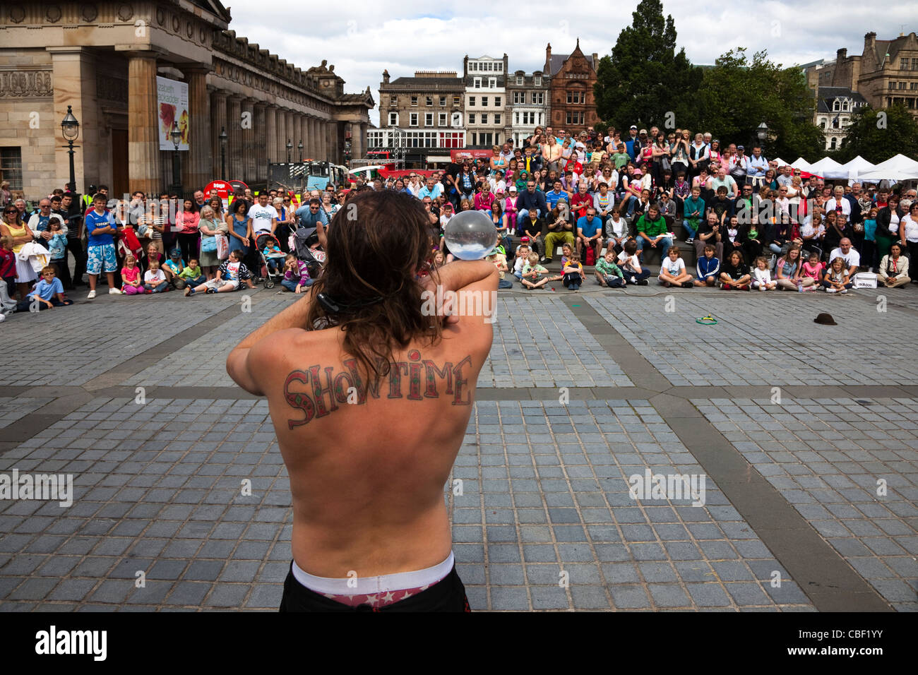 Animatore di strada al Edinburgh Fringe Festival con un tatuaggio di 'Showtime' sul suo retro Foto Stock