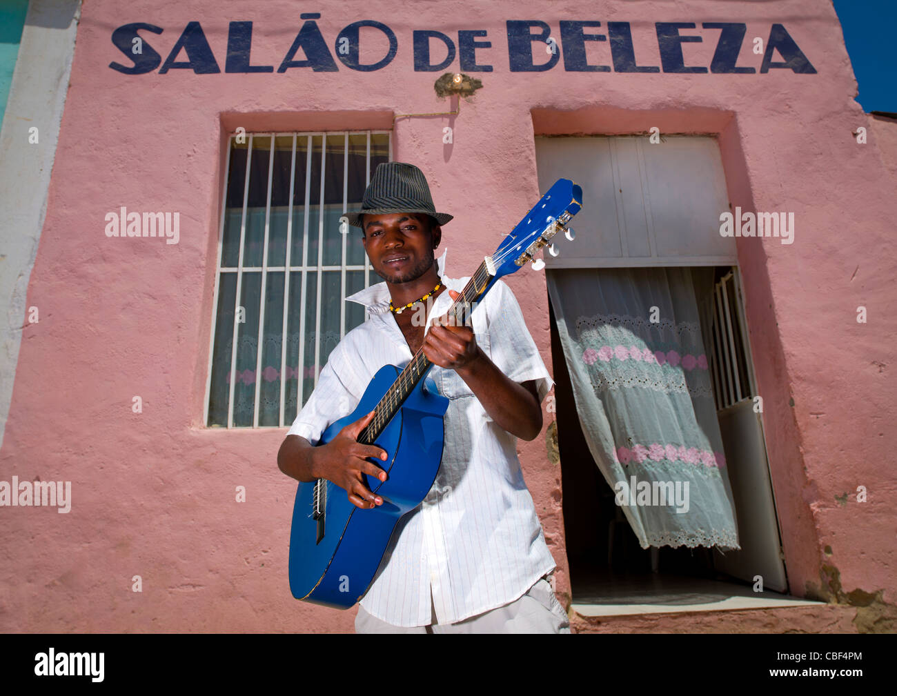 L'uomo con il cappello a suonare la chitarra nella parte anteriore di un Salone di bellezza, Angola Foto Stock