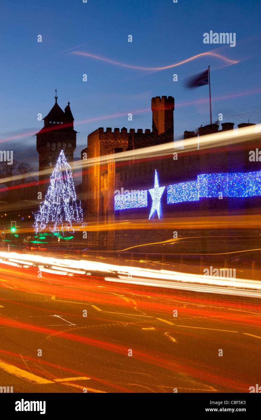Il Castello di Cardiff durante la notte con le luci di Natale / decorazioni e percorsi di traffico in primo piano Cardiff South Wales UK Foto Stock