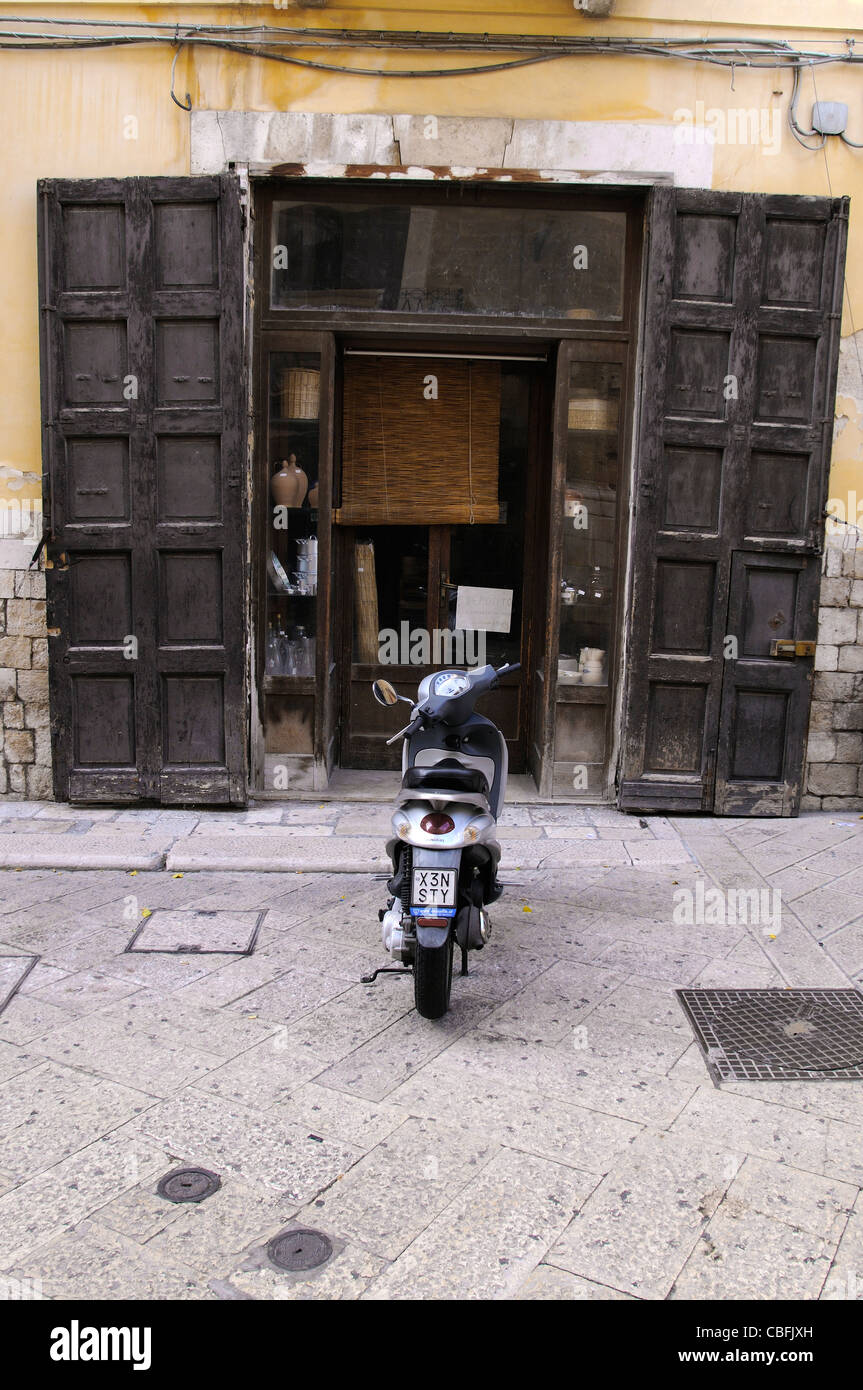 Scooter parcheggiato al di fuori del vecchio negozio italiano a Bari Foto Stock