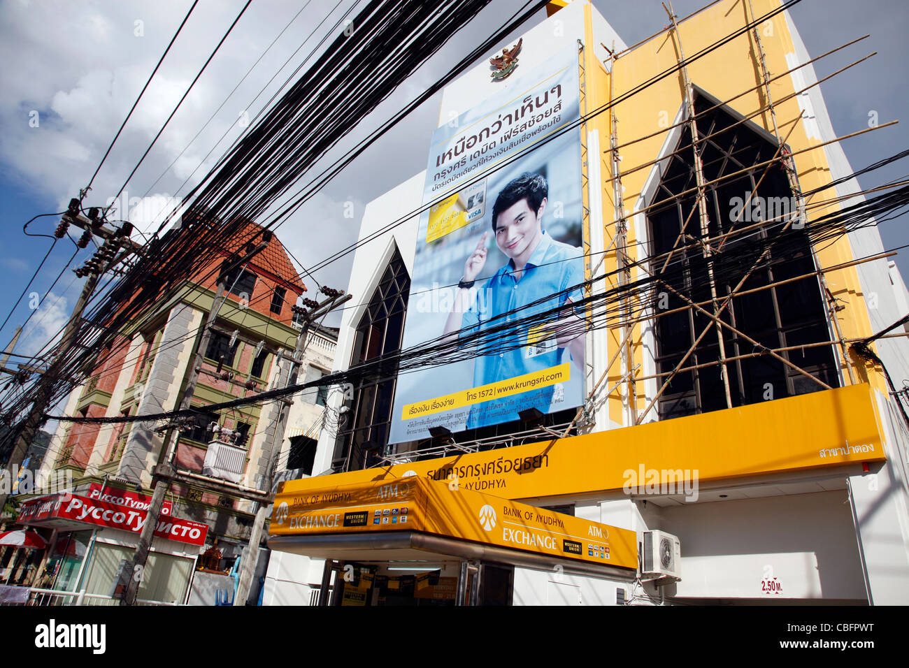 Un cartellone pubblicitario sulla banca di Ayudhya con energia elettrica i cavi di alimentazione a Patong, Phuket, Tailandia Foto Stock